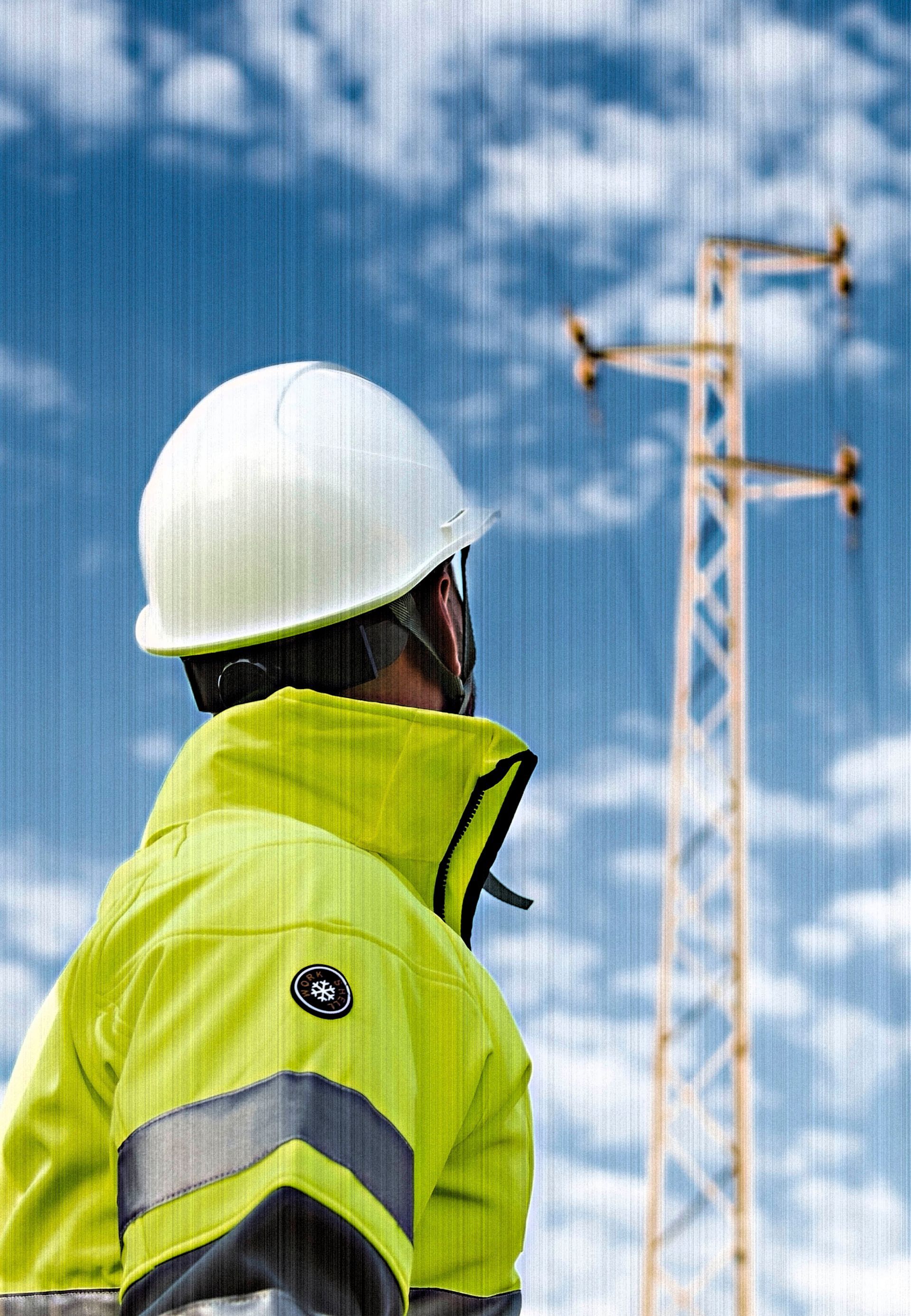 Un hombre que lleva un casco mira una línea eléctrica.