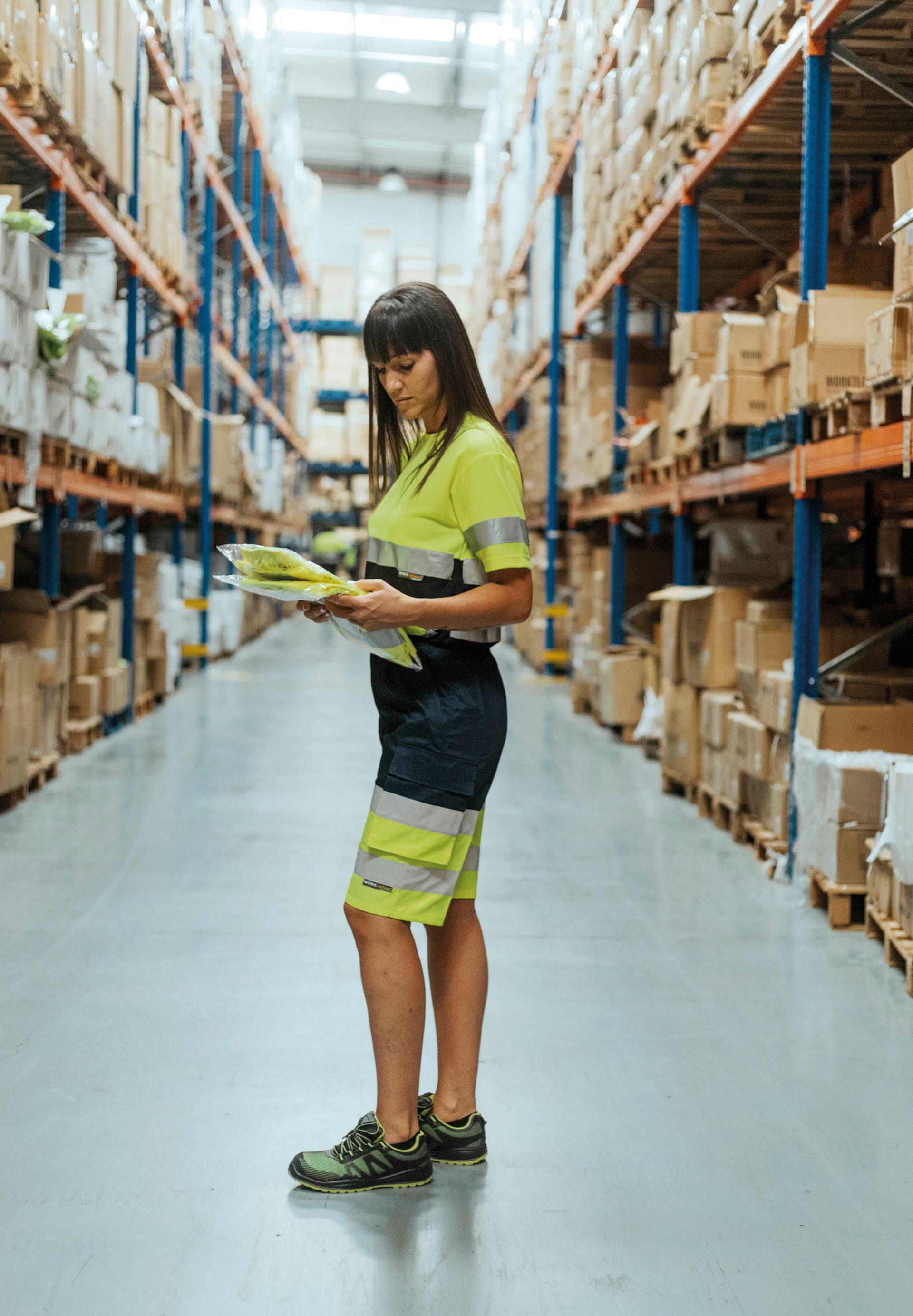 Una mujer está parada en un almacén mirando un portapapeles.