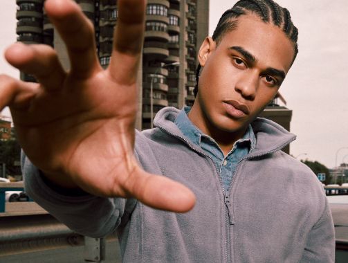 Un hombre con una chaqueta gris extiende su mano.