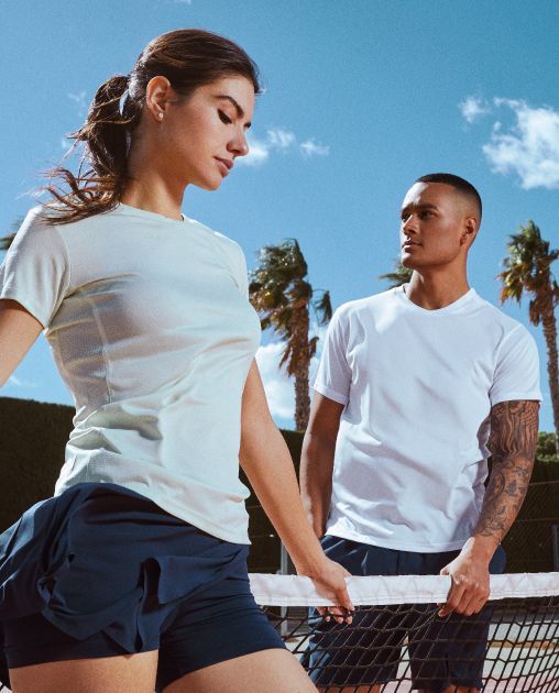 Un hombre y una mujer están parados uno al lado del otro en una cancha de tenis.