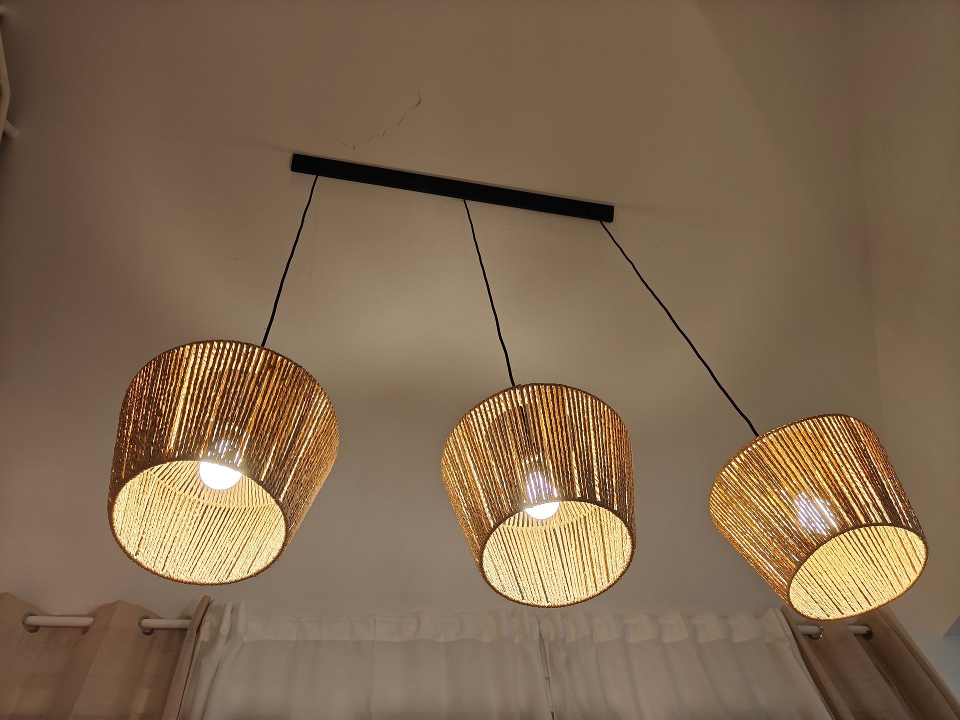 Deckenlampe mit drei geflochtenen Lampenschirmen im warmen Licht