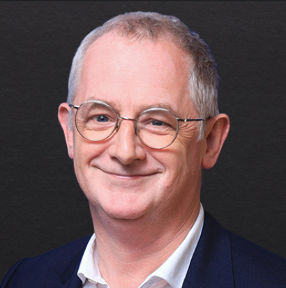 François-Xavier CARDON portant des lunettes et un costume sourit à la caméra.