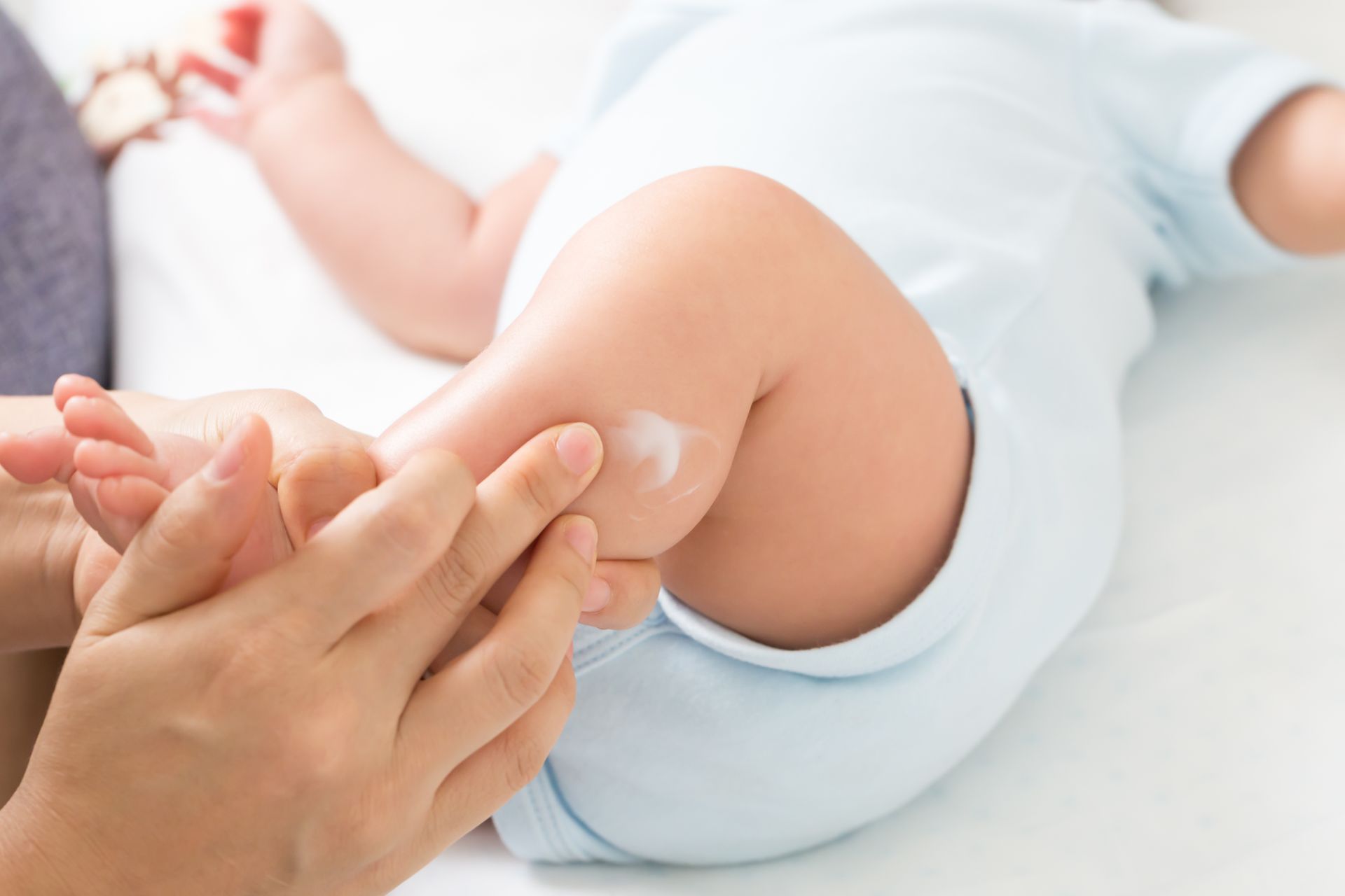 Une mère passe de la crème sur la jambe de son bébé