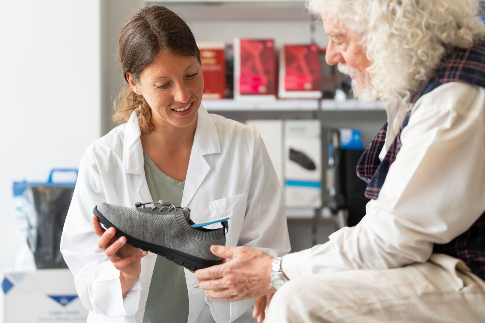 Une pharmacienne qui conseille un client sur des chaussures orthopédiques