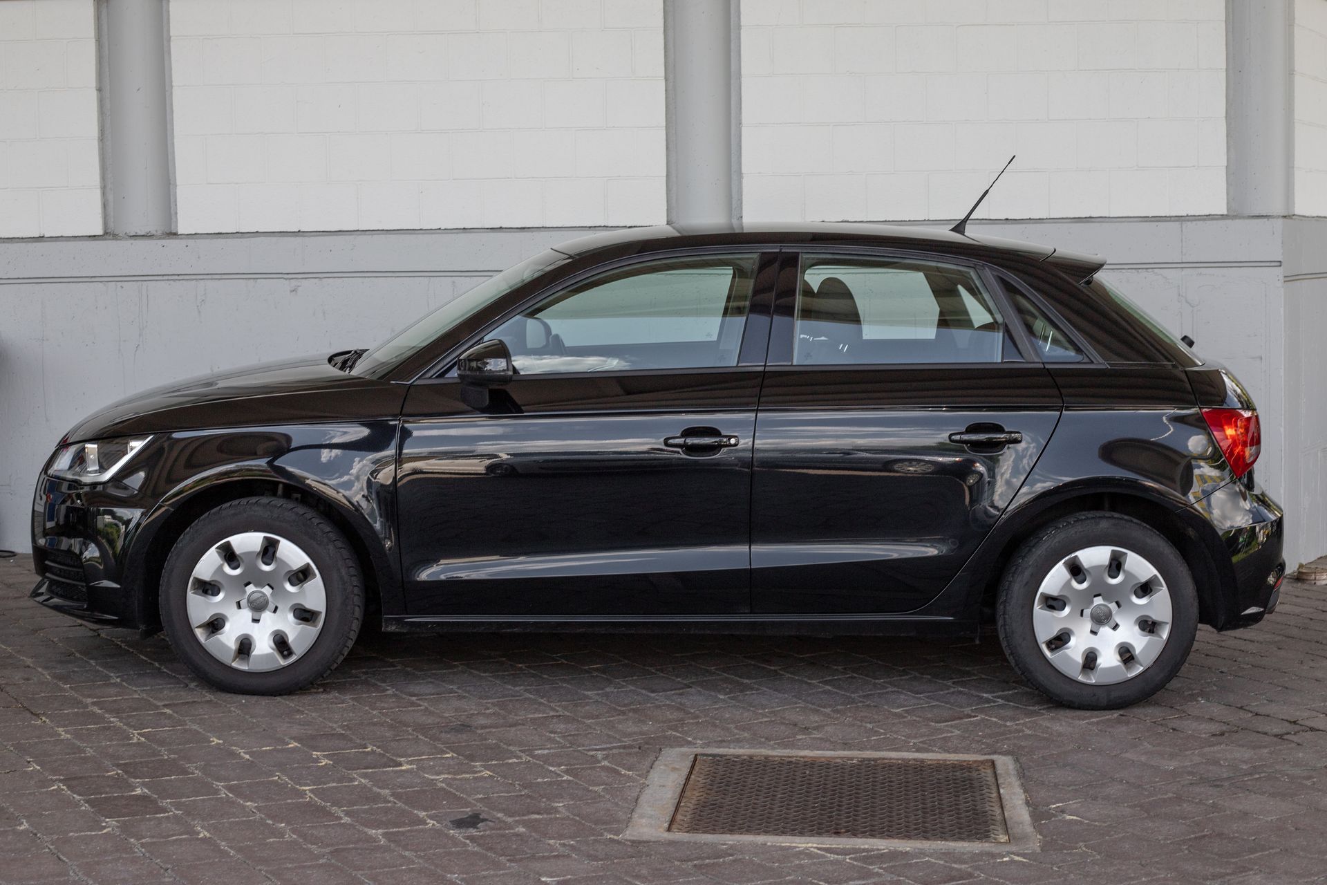 Fahrzeugmodelle Schwarze Kompaktlimousine, geparkt in einer Garage vor einer weißen Wand, Seitenansicht