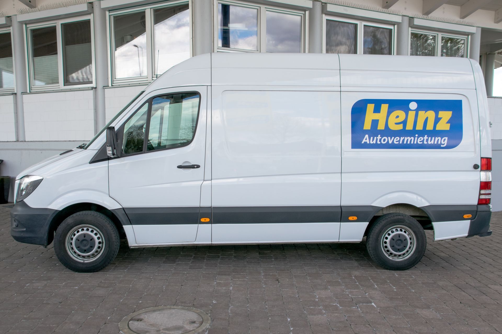 Fahrzeugmodelle Oranger Kompaktwagen mit Schrägheck, geparkt auf einer gepflasterten Straße, Seitenansicht