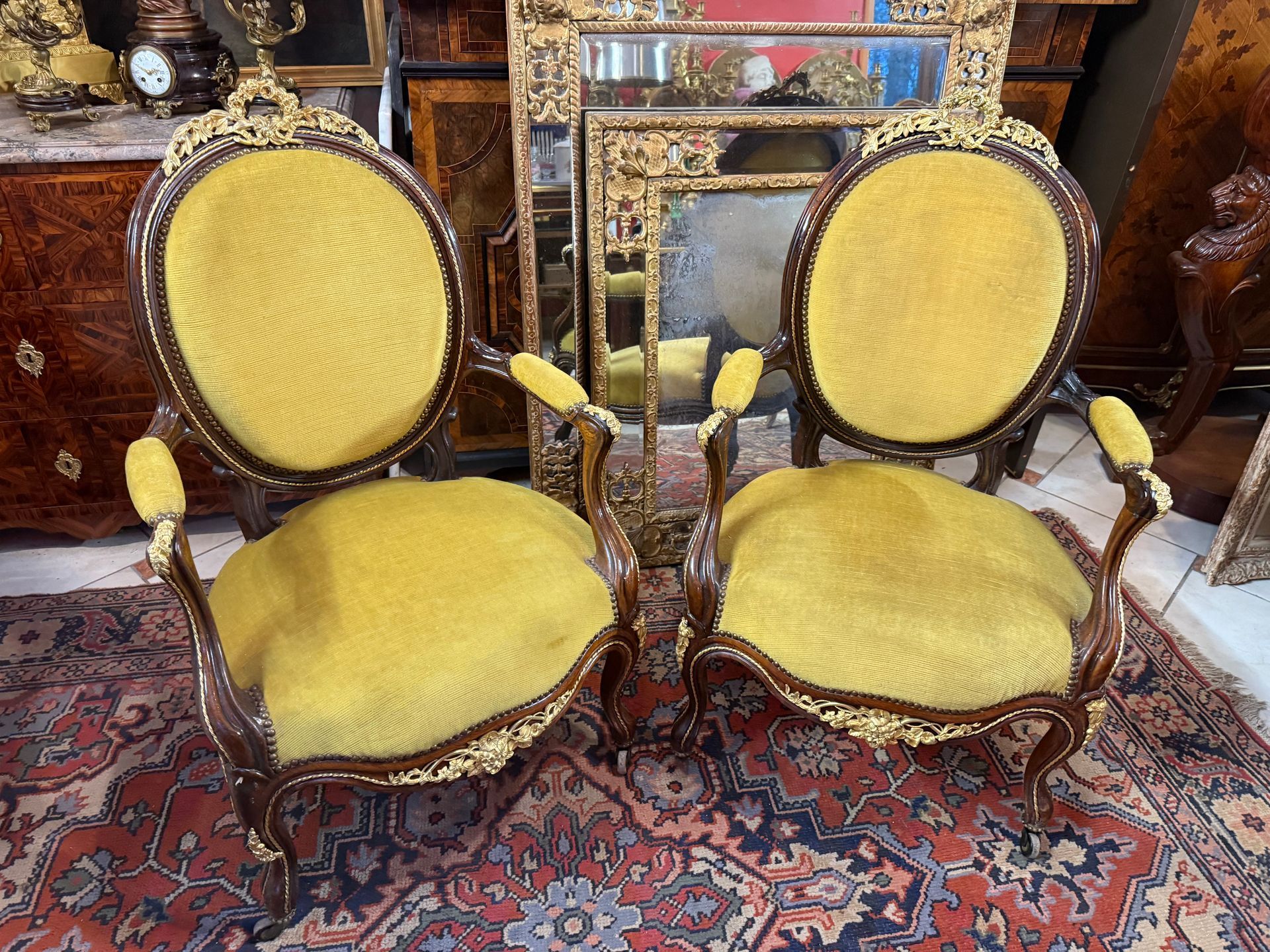 Paire de fauteuils à médallon et accoudoirs, Louis Philippe époque Napoléon III, à riche décor de bronze doré finement ciselé de rubans noués et fleuris, rais de perles, 
Recouverte d'un velours jaune, état d'usage.
Cette paire repose sur des pieds cambrés avec roulettes,