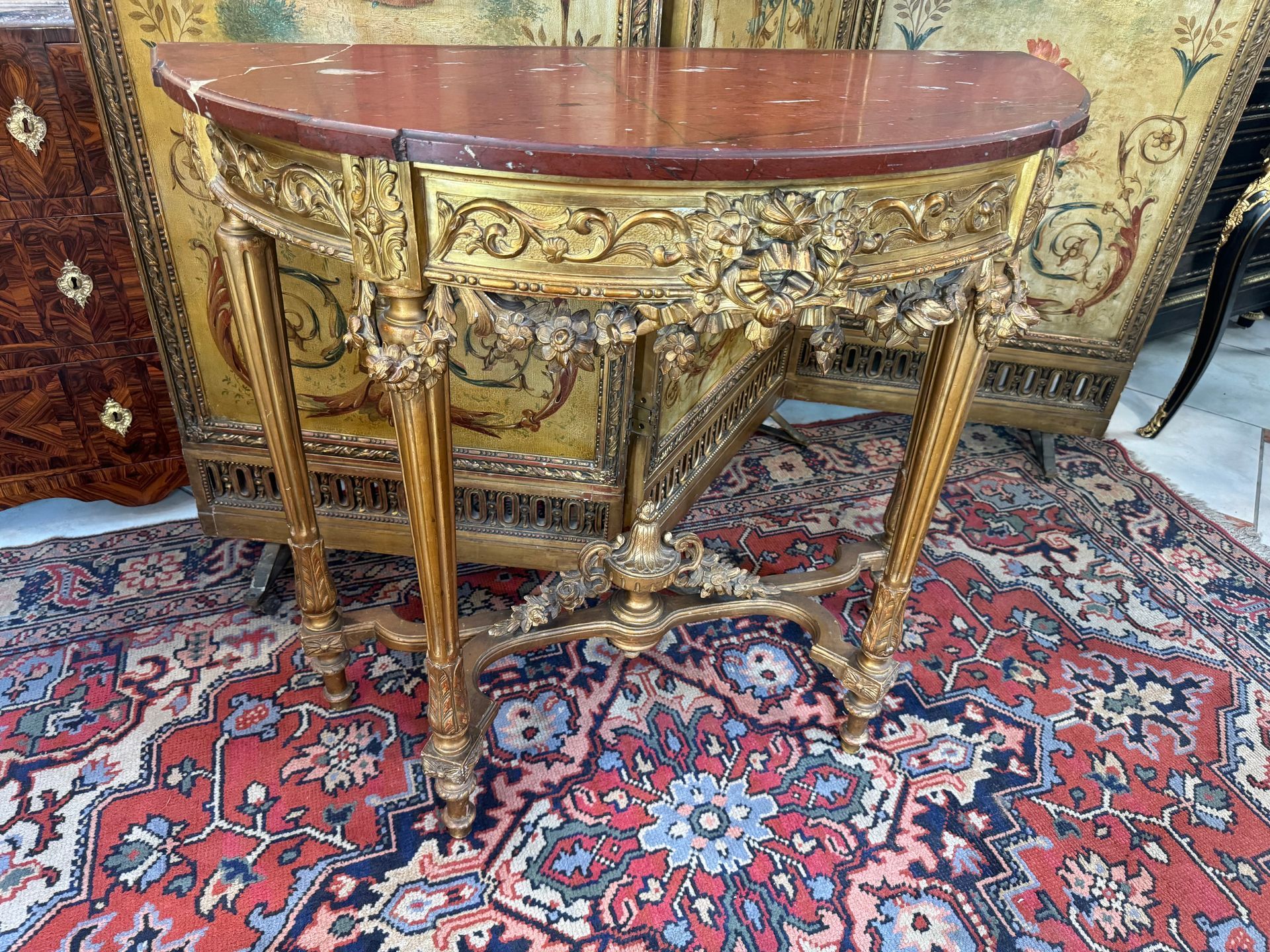 Table console , époque Napoléon III, 19ème,
en bois doré richement sculpté, décor floral, guirlandes de fleurs dans son ensemble bas et en ceinture, nœud Louis XVI, arabesques,
reposant sur des pieds fuselés à cannelures, avec entretoise réunie par une cassolette.
Le tout coiffé d'un marbre griotte .