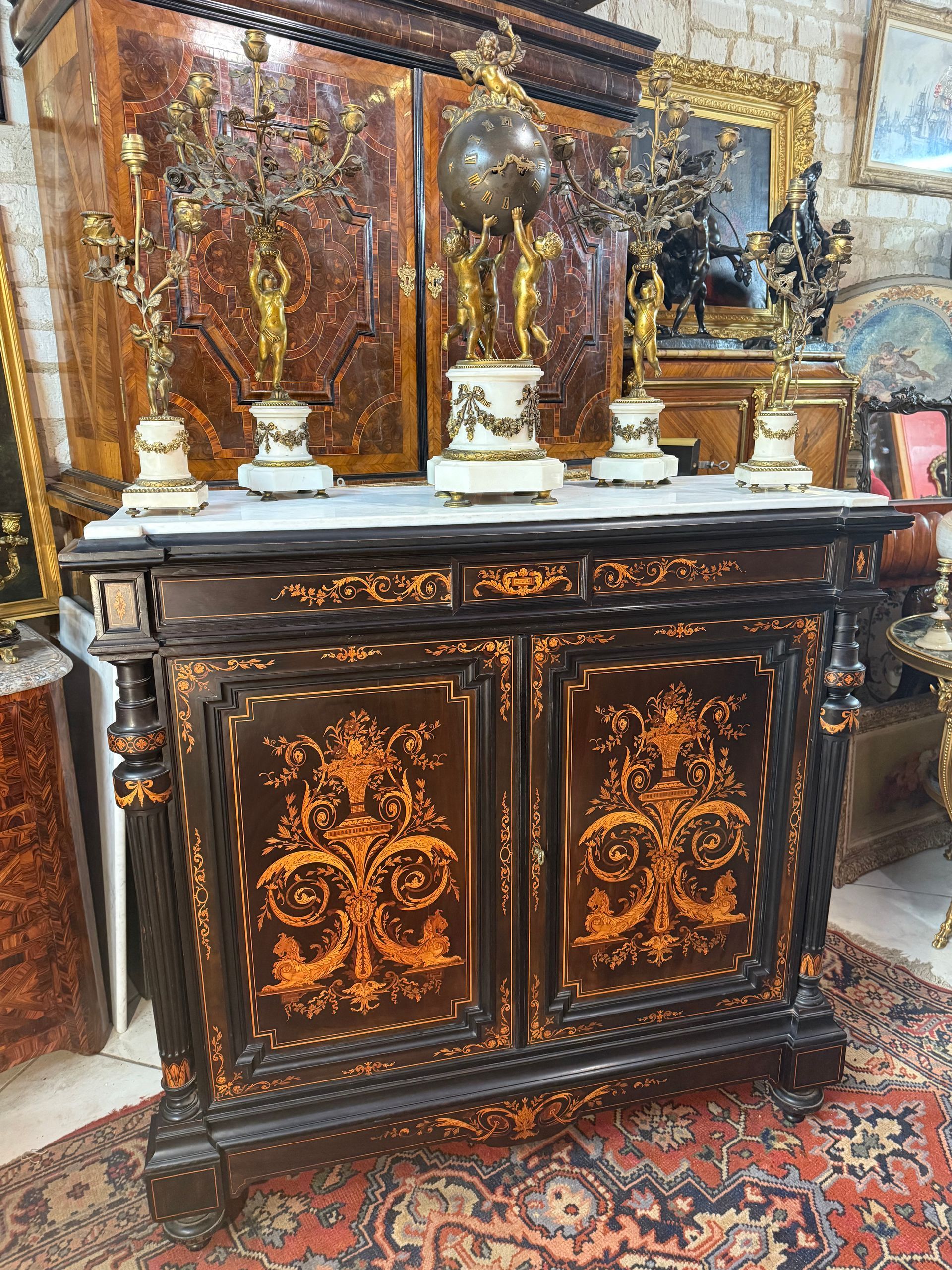 Meuble à hauteur d'appui de style Louis 16 d'époque Napoléon lll, en bois teinté noir,
Ouvrant par deux portes, Intérieur en placage de palisandre avec deux étagères réglables,
Colonne détachée et cannelée à noeud Louis 16 sur les côtés,
Riche marqueterie de qualité en façade en bois indigène de couleur claire représentant cassolette de fleurs, feuillage, lion ailé, 
Reposant sur pied dit toupie
Et coiffé d'un marbre blanc encastré,
IMeuble en très bon état de conservation et de belle facture.