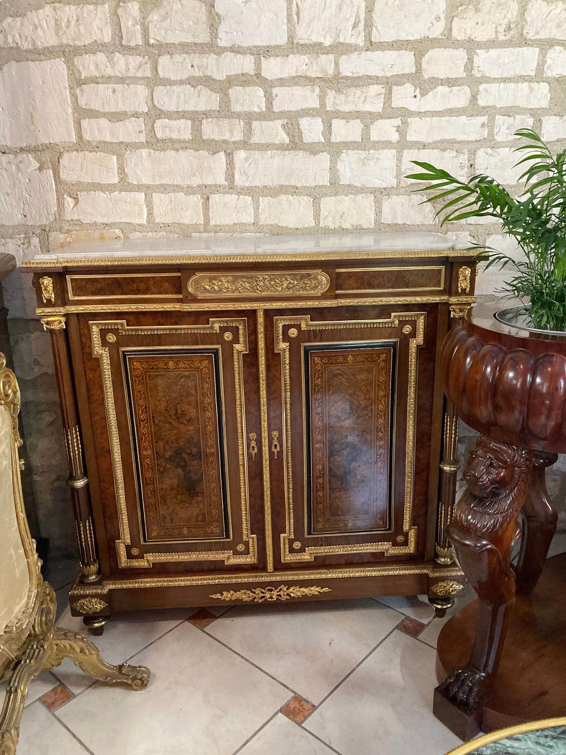 Très beau meuble à hauteur d'appui de style Louis XVI, Napoléon III, 19ème, en palissandre et loupe de noyer,
Il ouvre à deux portes avec un joli décor floral sur chacune des portes et présentant un intérieur avec deux étagères, possède sa clé,
Il offre une riche diversité de bronze doré savoir :
- tête de bélier de chaque côté,
- en façade un décor représentant une scène d’angelots.
- diverses et importantes frises : en ceinture , dans l’encadrement au niveau du marbre, dans le pourtour de chaque porte avec une frise de petites perles et encadrement en bois noirci, dans la partie basse décor de feuillages avec nœud,
- petites fleurs,
- sur les montants des colonnes de chaque côté avec bague,
Le tout repose sur des pieds toupies,
Et coiffé d’un marbre blanc épais encastré.
Travail de belles facture et qualité.