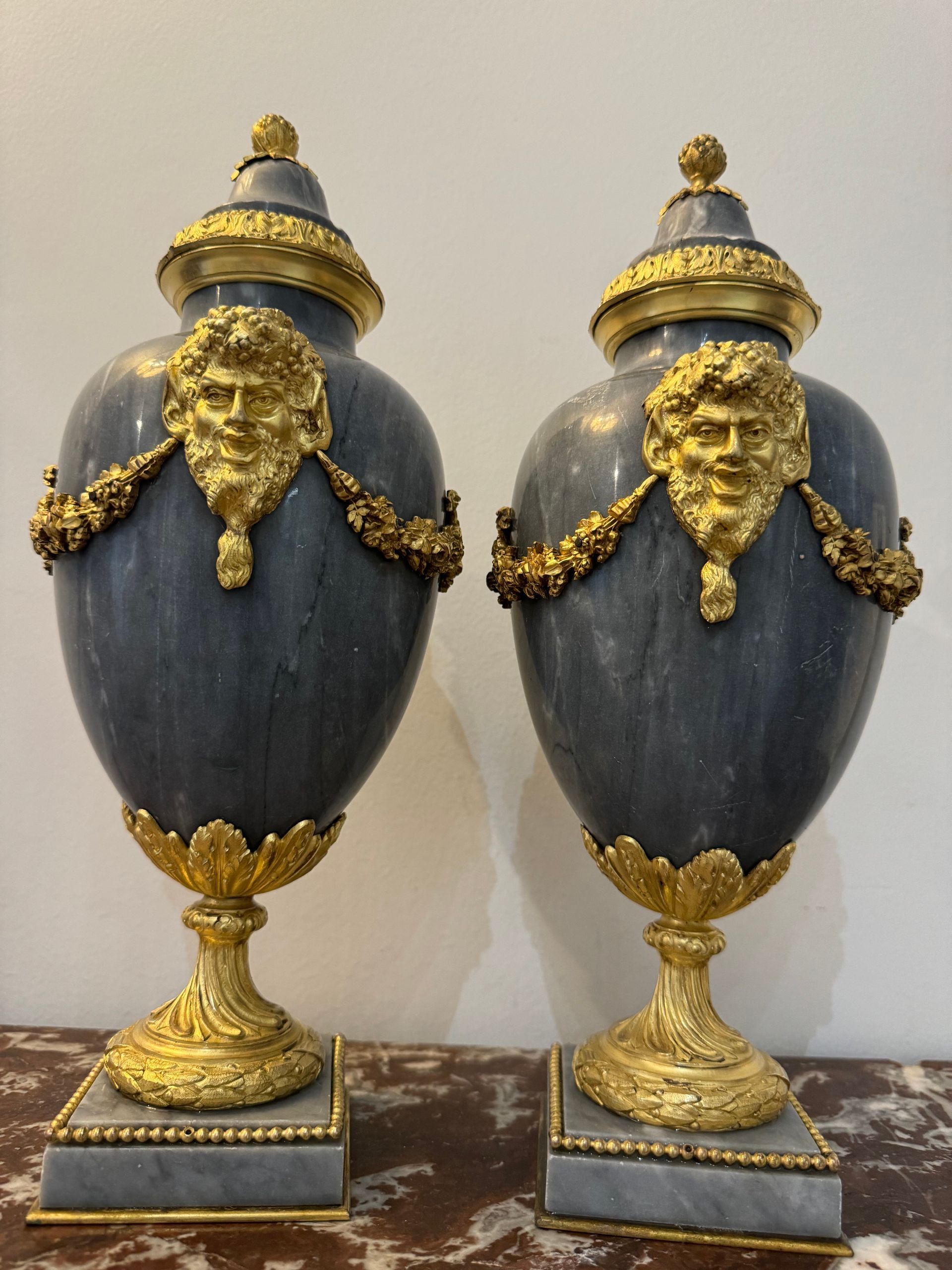 Jolie paire de cassolettes de style Louis XVI, 19ème siècle.
En marbre bleu de turquin,
De forme ovoide,
Cette paire sur socle carré avec frise, repose sur pied douche et présente une riche et belle parure de bronze doré finement ciselé, flanquée de tête de faune, frise au col, et guirlande de fleurs, 
La prise du couvercle se termine par une pomme de pin.
Objets très décoratifs.