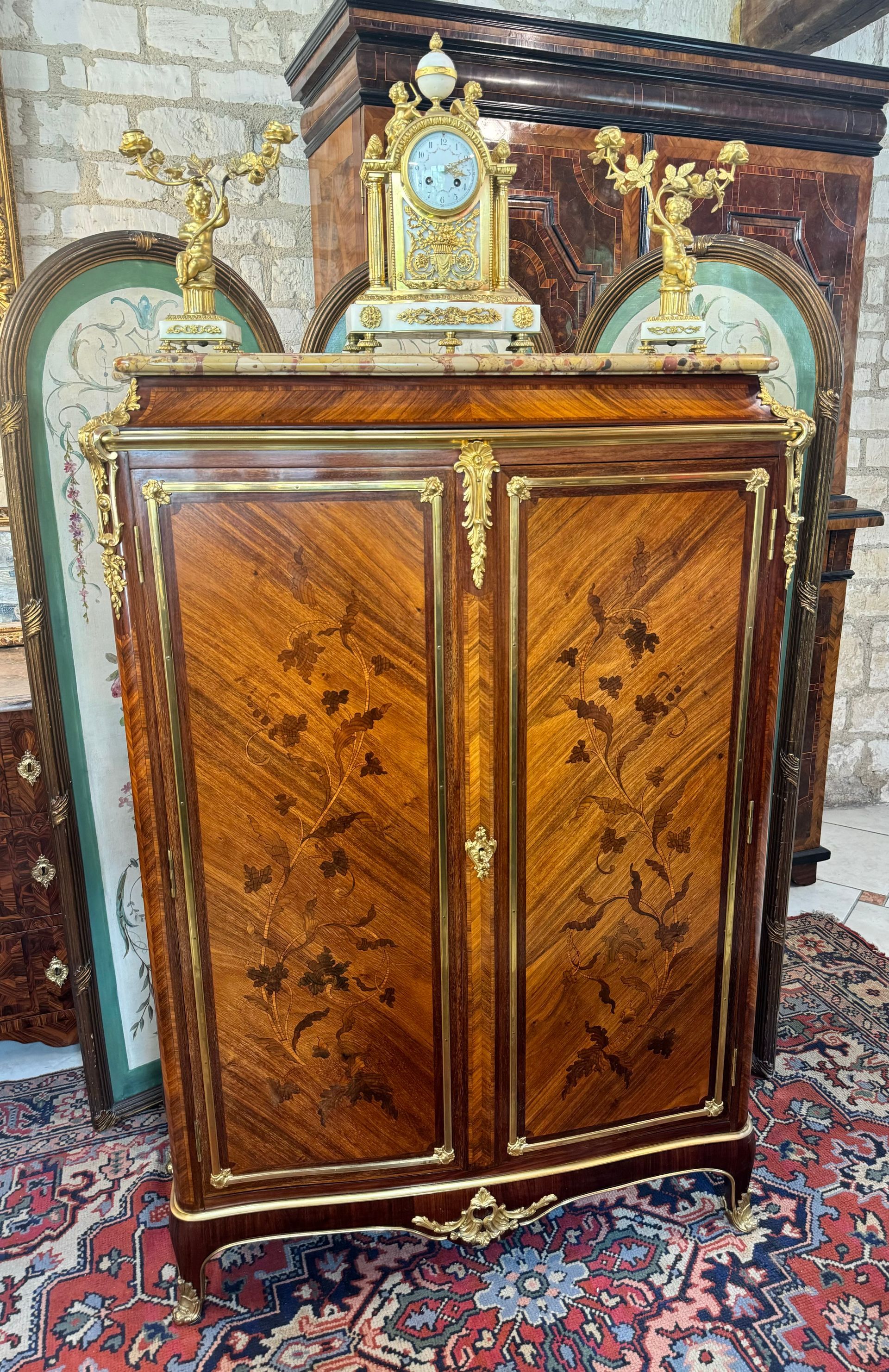 Jolie armoire basse Louis XV à doucine de forme mouvementée,
Ce meuble est marqueté de fleurs bois en bois de bout, présentant un riche décor floral face et côtés et de bronzes dorés dans son ensemble (Montant en partie haute, dans les encadrements, sabots et partie basse).
Il ouvre à deux portes et présente un intérieur avec trois étagères.
Le tout campant sur des pieds galbés et coiffé d’un marbre brèche.
Estampillé : G. DURAND
Gervais DURAND (1839-1911) célèbre ébéniste parisien,
Il exerce à partir de 1870 dans le faubourg Sain Antoine. En 1889 ,il participe à l'exposition universelle et son talent est récompensé par une médaille d'argent. Le rapport de l'époque dit de lui :