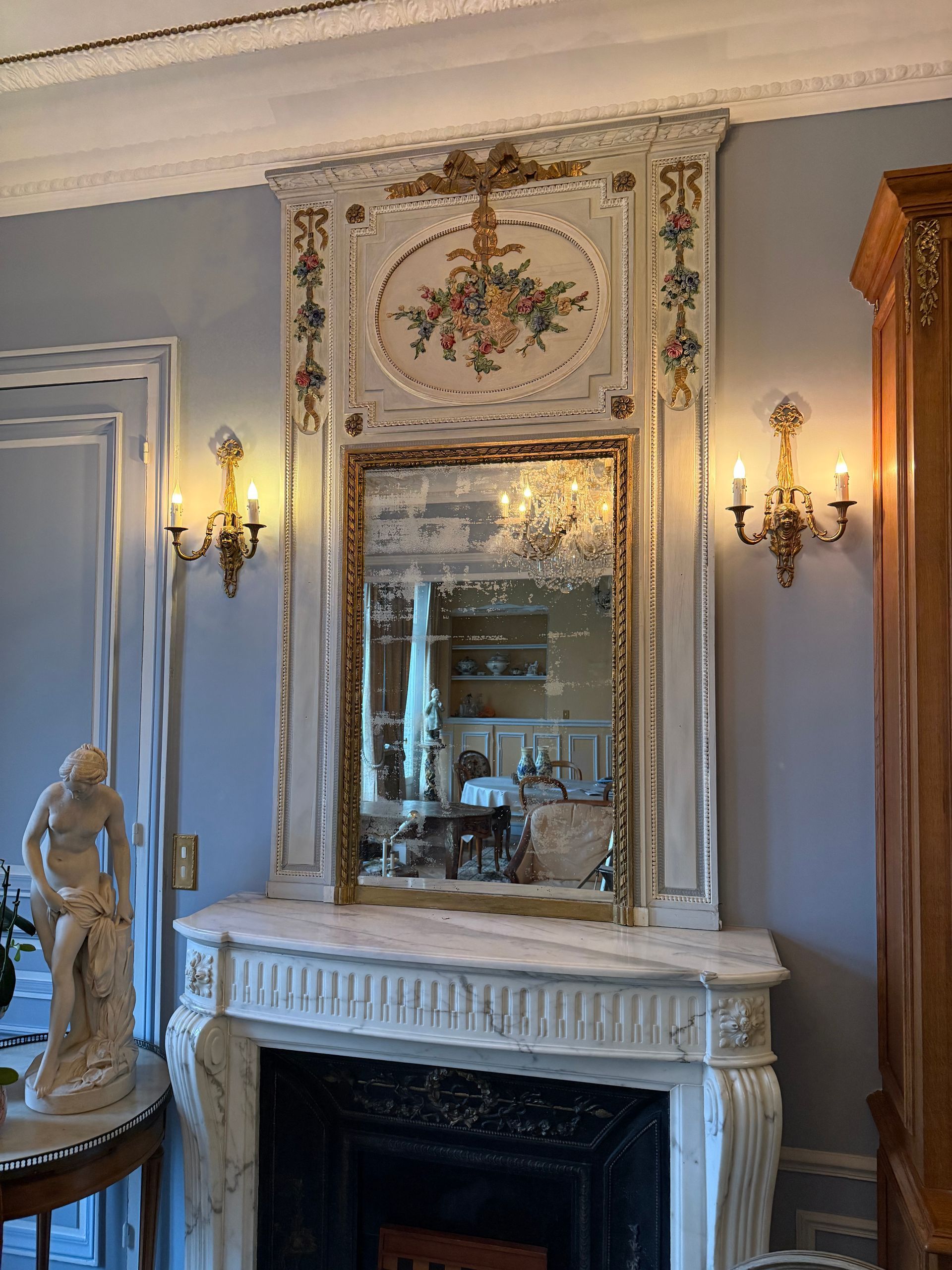 Grand Trumeau Louis XVI en bois laqué peint blanc et doré,
Ce trumeau présente dans son centre  un médaillon  floral soit un panier de fleurs peintes avec un pourtour d'une frise et nœud Louis XVI, petites rosaces de fleurs dorées, bois sculpté en haut.
Sur chaque côté dans son haut une guirlande de fleurs peintes,
Grand miroir avec différents  pourtours de frises de perle.
A noter que le miroir est d'origine légèrement piqué.
Ce grand trumeau provient d'un appartement parisien.
