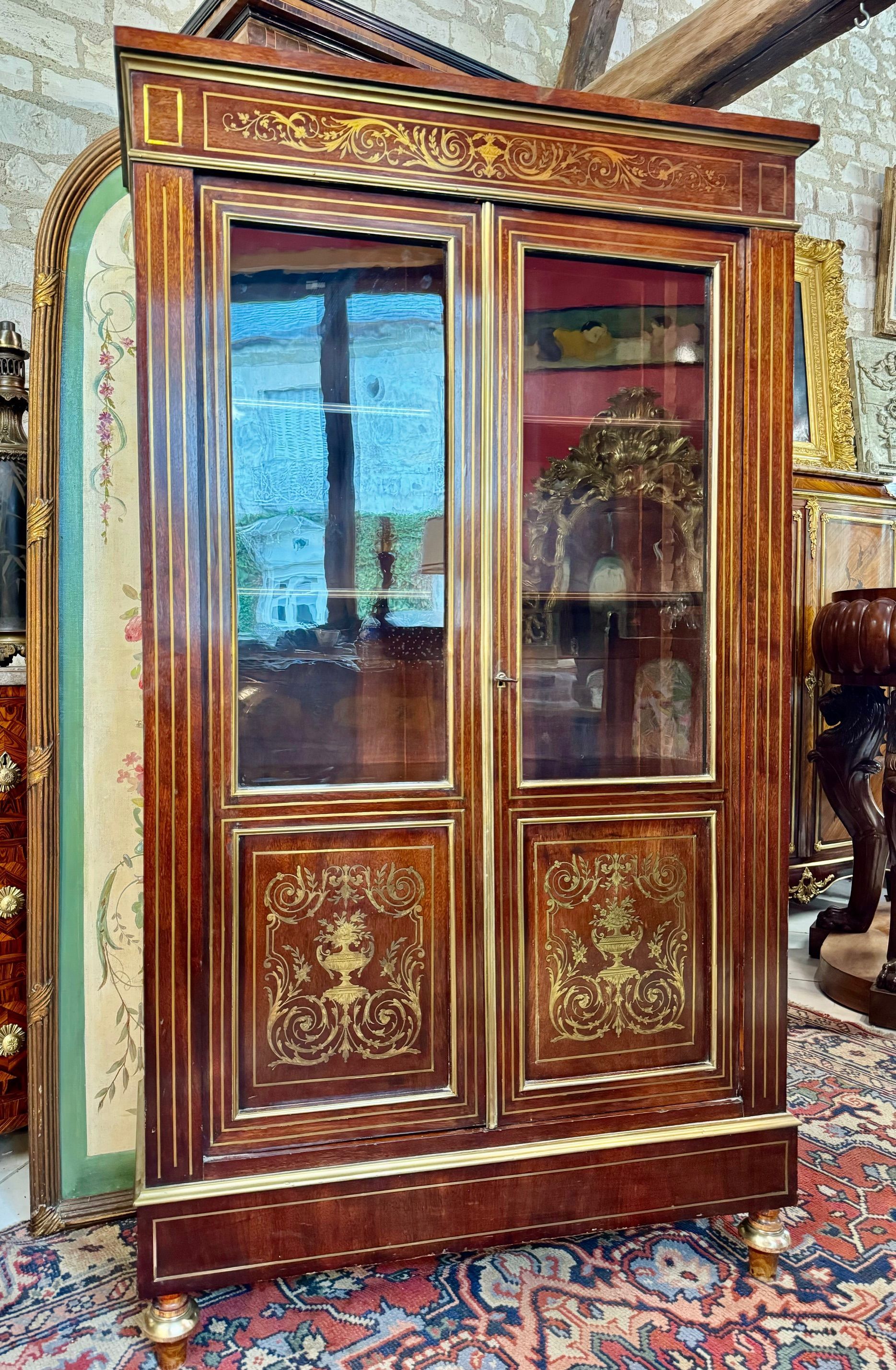 Petite et élégante bibliothèque pouvant également servir de vitrine de style LOUIS XVI - 19ème,
En placage de palissandre et marqueterie de bois clair.
Cette bibliothèque ouvre à deux portes vitrées présentant un intérieur avec quatre étagères.
Elle offre un riche décor d’entrelacs, fleurs, urne, rinceaux, acanthe, ... souligné de baguettes en laiton dans son ensemble
Reposant sur des pieds toupies.
Largeur: 91 cm,
Hauteur: 157 cm
Profondeur: 32 cm