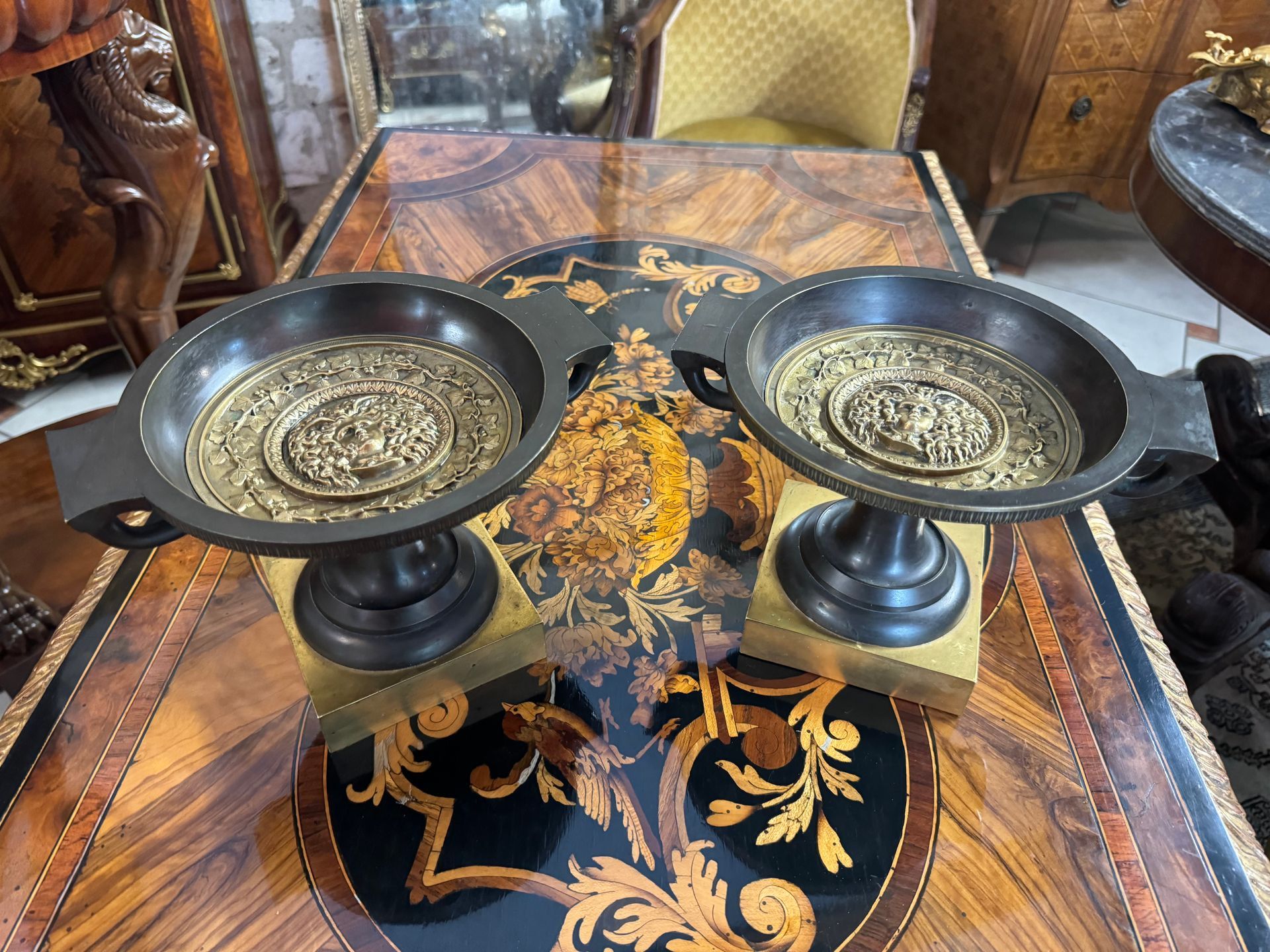 Paire de coupe EMPIRE, en bronze patiné et doré, sur pied surmonté d’un socle carré.
Coupe de forme ronde à anses de forme originale.
L’intérieur présente un décor de méduse enrubanné de feuilles de lierre.
Ensemble décoratif pouvant servir également de cassolettes ou de vide – poche.
