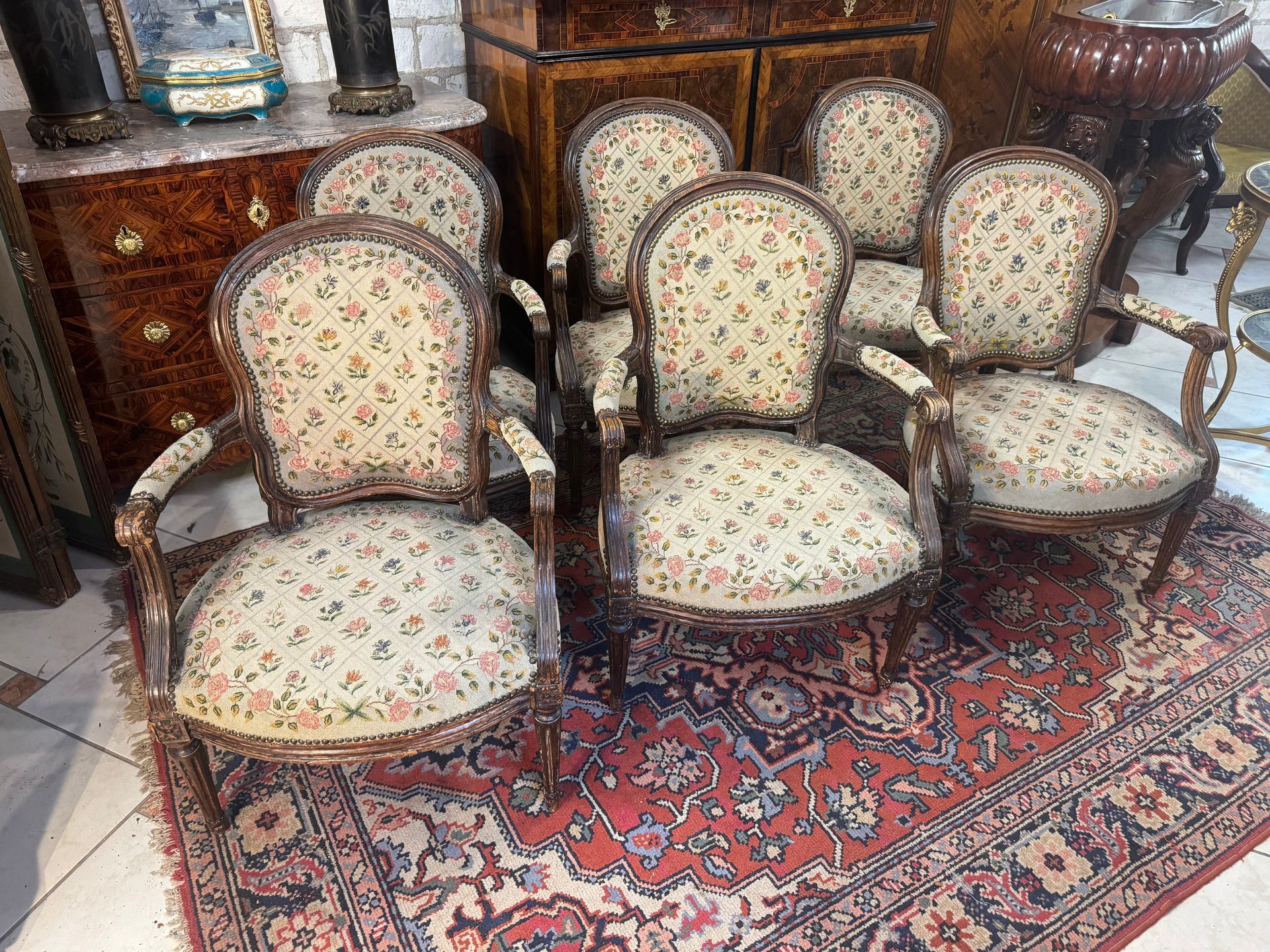 SUITE DE SIX FAUTEUILS ESTAMPILLE L. DELANOIS
EPOQUE 18ème   - LOUIS XVI
Suite de six larges fauteuils à médaillon en hêtre (ancienne patine) avec accotoirs à manchette,
Assise garnie d’une tapisserie à petits points à décor floral et clouté.
Les fauteuils reposent sur quatre pieds fuselés et cannelés.
Estampillé L. DELANOIS.
A noter : tapisserie état d’ usage - structure et assise en bon état 
A propos de :
Louis Delanois (1731-1792) – menuisier en siège – maîtrise obtenue le 27 juillet 1761 : Louis Delanois figure parmi les plus grands menuisiers du XVIIIème siècle – le plus inventif de la période Transition.
Louis Delanois laisse derrière lui un grand nombre de sièges, aussi bien de style Louis XV que Louis XVI, qui témoignent tous de son talent. Après ses débuts dans un atelier de la rue Bourbon-Villeneuve, le succès est rapidement au rendez-vous et il décide de s’établir rue des Petits Carreaux, où, parallèlement à son activité principale, il pratique le commerce du bois. Delanois travaille pour des marchands, pour d’illustres personnalités comme le comte d’Artois, le prince de Condé ou le duc de Chartres, pour de riches collectionneurs mais surtout pour la comtesse du Barry, qui lui passe de très nombreuses commandes.