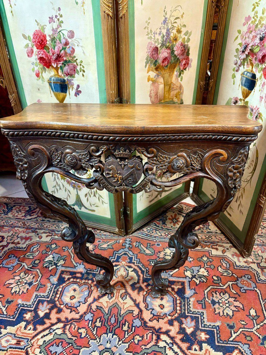 Petite console galbée en chêne début 19ème, 
La ceinture est richement sculptée avec un décor représentant un blason aux emblémes de la couronne et lion (Homos-Armis), et fleurs de rose,
Le plateau en chêne présente une frise en pourtour.
le tout soutenu par deux pieds cambrés eux-mêmes richement mouvementés et sculptés.
Beau travail du Nord de la France.
