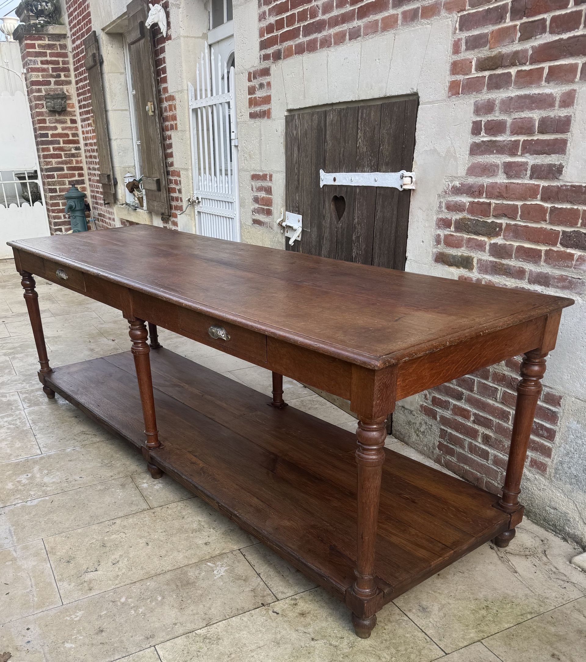 Ancienne table de drapier du 19ème, en chêne massif, Cette table est dotée d’un double plateau et de deux tiroirs de rangement. Elle repose sur six pieds. Cette table peut servir d’îlot central, présentoir dans un salon, dans une cuisine, une boutique, de confection, de découpe, un restaurant etc.... Table robuste de belle facture provenant d’une mercerie dans le Nord de la France.