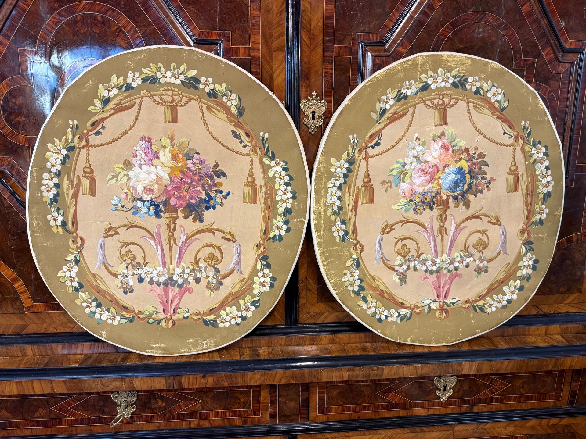 PAIRE DE TABLEAUX  de style Louis XVI - 19ème, de forme ovale.
Peinture sur toile, répresentant dans son enemble un joli décor floral de différentes fleurs, corde avec son pompon, dans les tons doux et de  couleurs pastel.