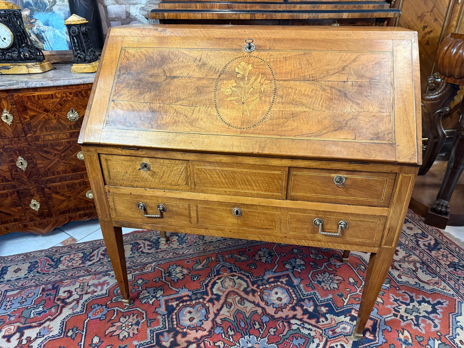 Bureau de pente d’époque Louis XVI DIRECTOIRE – 18ème, en noyer massif.
Ouvrant en façade par quatre tiroirs sur deux rangées, (trois et un grand), poignées de tirage sur le grand tiroir.
Façade à décor de médaillon floral.
Offrant un intérieur présentant une étagère, quatre petits tiroirs, un tiroir secret dans son milieu et abattant en cuir noir avec décor doré de losange et pourtour de frise , lequel fait office d’une table d’écriture-bureau. (table d'écriture 39cm)
Le tout reposant sur des pieds gaine terminés par des petits sabots.