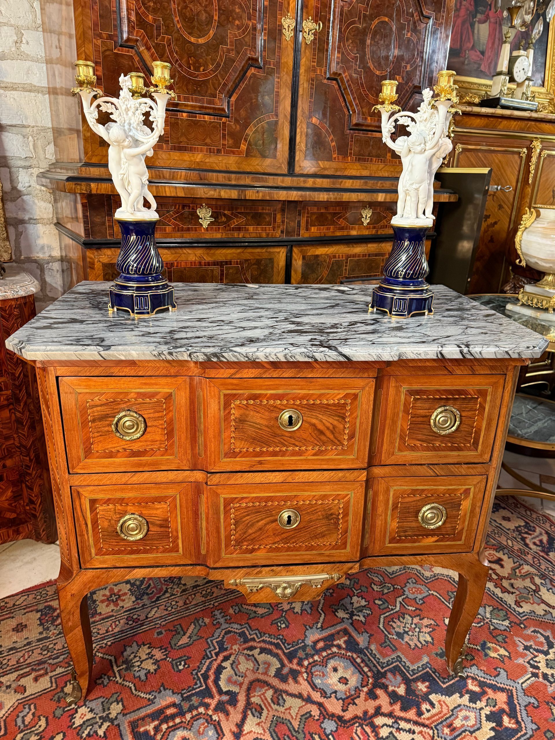 Elégante commode dite sauteuse d’époque Louis XVI - XVIIIe siècle, en placage de noyer, Ouvrant à deux tiroirs sur deux rangées avec des petites poignées de tirages en anneaux,
Offrant un riche décor à motif de frisages dans des encadrements et filets verts.
 Reposant sur des pieds cambrés.
Le tout coiffé d’un marbre bleu turquin.