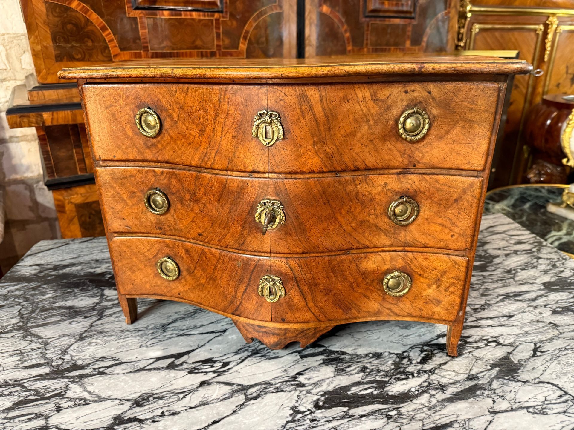 Commode de maîtrise de style Louis XV - 18ème siècle,  en noyer, de forme galbée en facade,
Elle ouvre  par trois petits  tiroirs avec des poignées en anneaux et petites entrées forme de petits noeuds, possède sa clé (serrures et clé d'origine).
Plateau bois mouvementé, 
Le tout reposant sur des pieds droits.