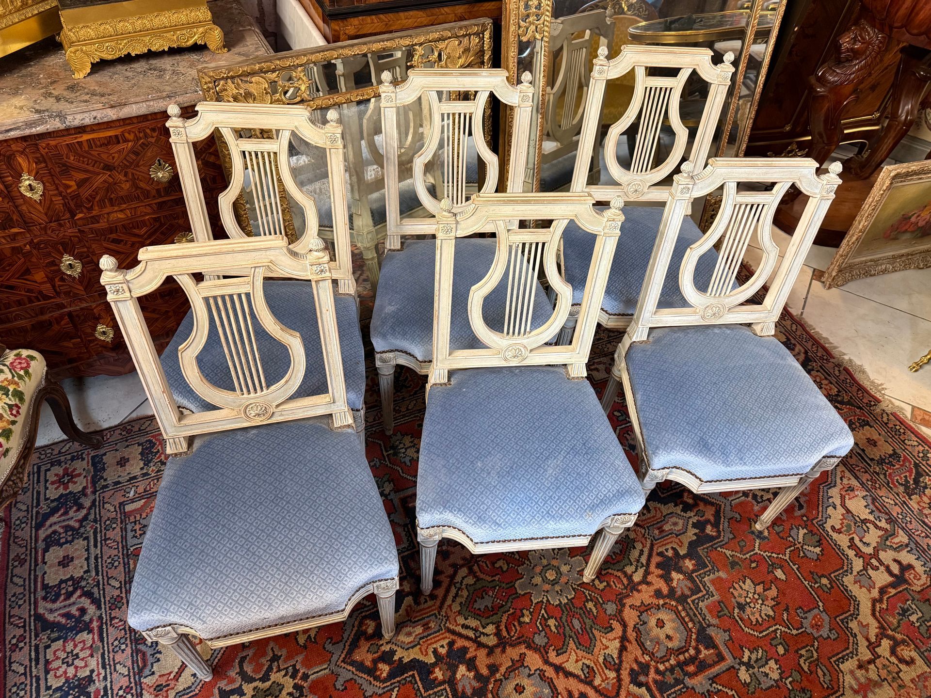 Série de six chaises en bois peint réchampi bleu de style Louis XVI à dossier lyre,
Assise recouverte d'un velours bleu à losange clouté,
Reposant sur pieds cannelé, décor de petite rosace,
la structure et l'assise  sont en bon état;
