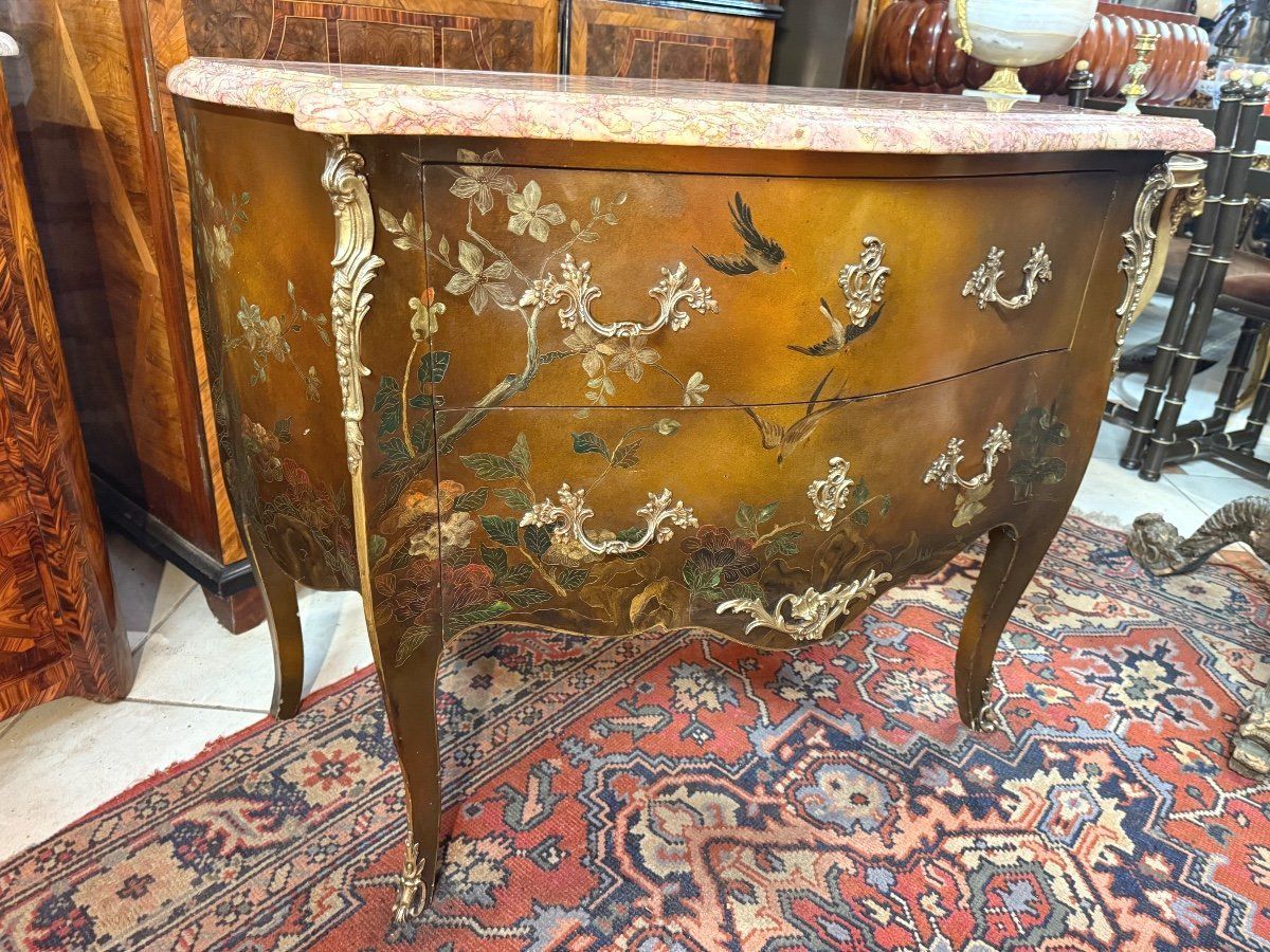 Jolie commode de style louis XV en laque de chine à décor de volatiles et de fleurs,
Poignées et chutes de bronze ciselées et dorées,
cette commode est galbée en façade et sur les côtés, 
Elle ouvre par deux tiroirs sans traverse;
Structure en chêne,
le tout coiffé d'un marbre brèche;
Travail parisien début 20ème du Faubourg Saint Antoine