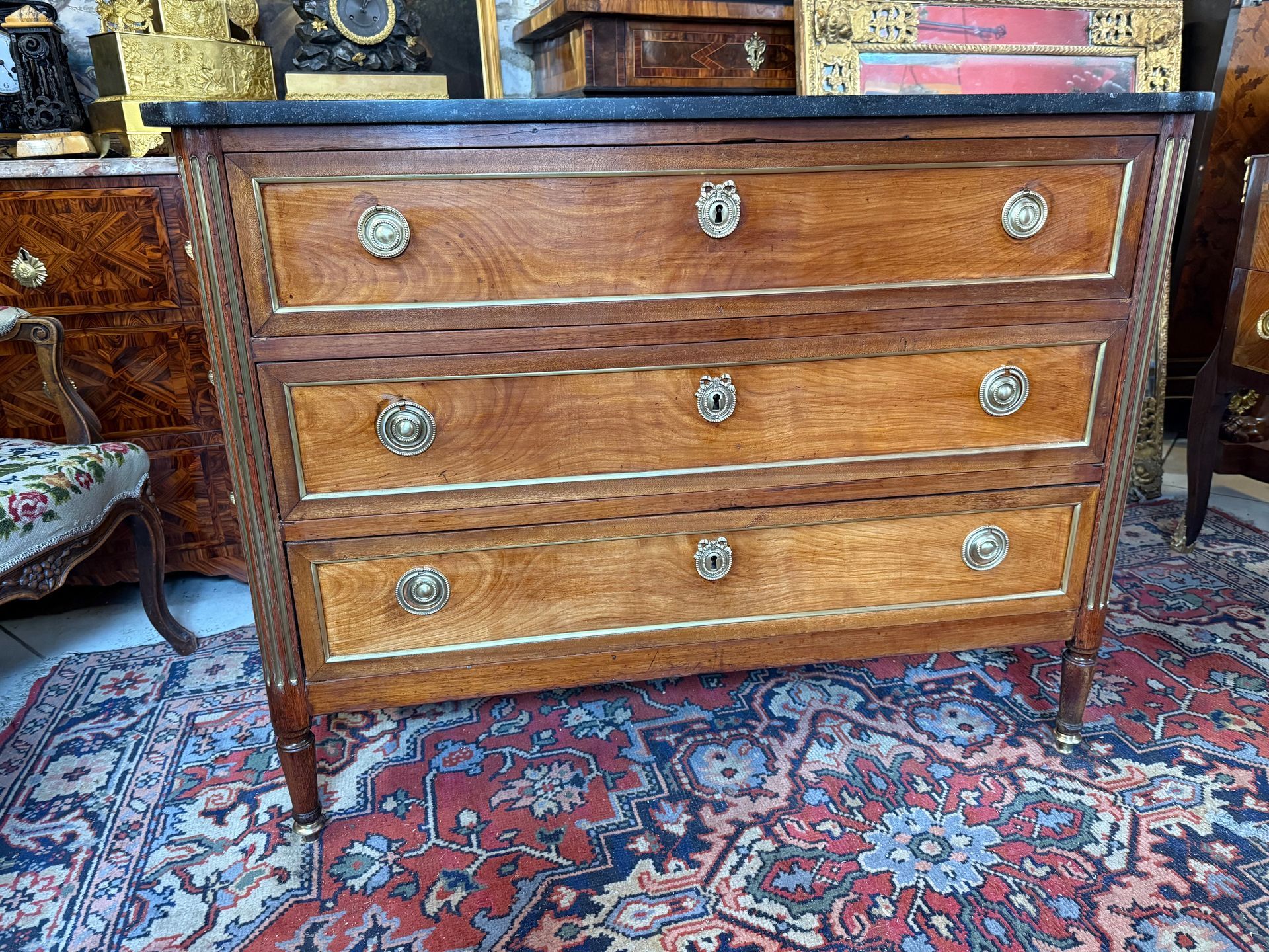 Commode d'époque Louis XVI - 18ème, en merisier, structure en sapin, avec un décor de baguettes de laiton dans les encadrement de tiroir et sur les côté et cannelures en laiton dans les angle,
Elle ouvre part trois grand tiroir , sur trois rangs, poignées de tirage en anneaux et petites entrées de serrure,
le tout reposant sur pieds à cannelés , 
et coiffé d'un marbre brèche Saint-Anne.