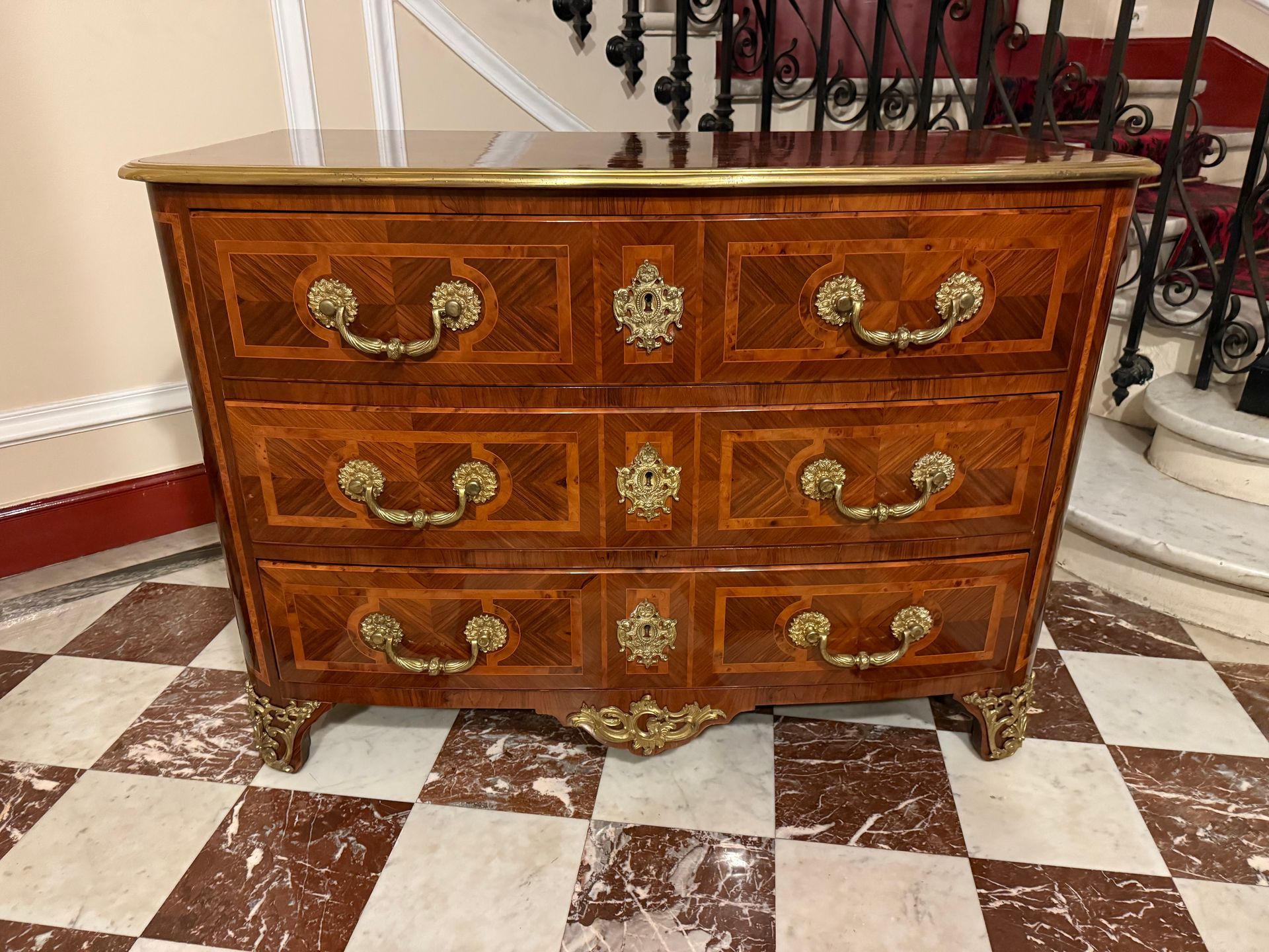 Commode de style Louis XIV - fin 19ème début 20ème, en placage de palissandre et d'olivier dans les encadrements,
Elle ouve à trois grands tiroirs sur trois rangées, avec des poignées tombantes et petites fleurs,
Lingotière en laiton,
Les cotés et le plateau sont à décor gèomètrique.
Ornementations de bronze sur le bas des pieds et sur la traverse du bas.
Meuble de la fin 19ème travail du faubourg Saint-Antoine de belle facture.