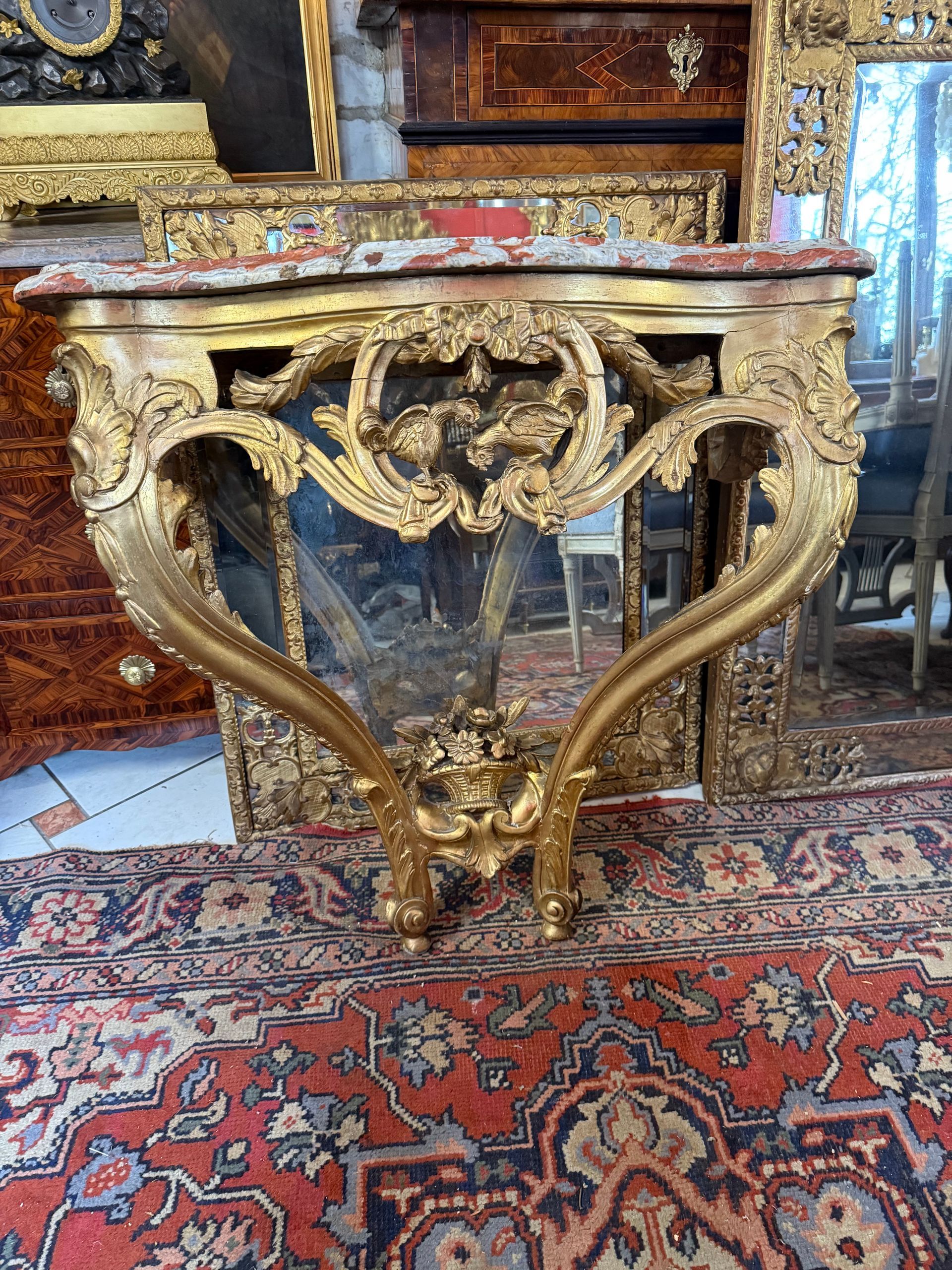 Jolie console d'applique, louis XV - 18ème  de forme mouvementée, en bois richement sculpté et doré dans son ensemble.
Elle offre une traverse centrale  sculptée dévoilant dans son centre ajouré des motifs floraux, deux volatiles, noeud, 
Rinceaux sur les montants, décor ajouré floral sur les côtés.
Les deux pieds cambrés sont reliés par une entretoise formée d'un panier de fleurs, 
La console est coiffée par son marbre rouge du languedoc.
Travail français.