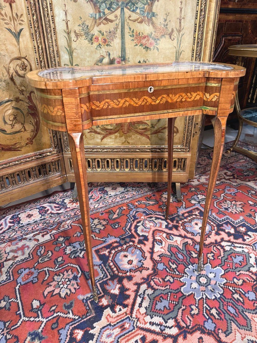 Élégante table de forme rognon,  formant vitrine (bjouterie et/ou argenterie)  et écritoire d'époque 18ème, de style Louis XVI, 
 En placage de bois de rose, amarante et bois teinté, marqueterie à décor d'enroulement et de feuille.
Entrée en ivoire,
Pieds cambrés,