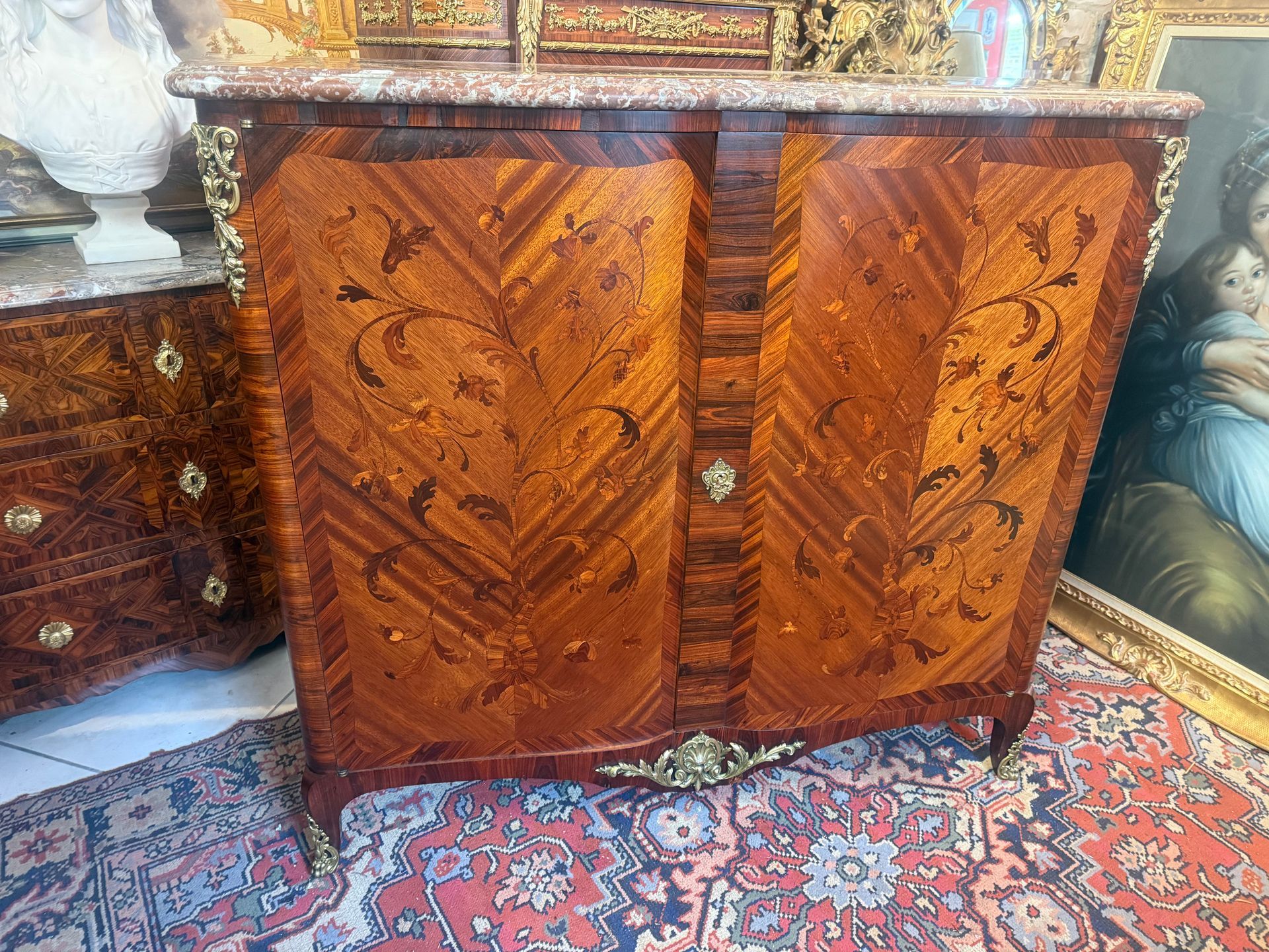 Buffet à hauteur d’appui de style Louis XV, fin 19ème,  Différentes essences de placage de palissandre et marqueterie forale de bois de bout en façade et sur les côtés, Structure en chêne,  Ce buffet est galbé en façade et sur les côtés, ouvrant à deux grands vantaux, présentant un Intérieur avec deux étagères,  Il offre des chutes de bronze sur les montants du haut , sur la traverse du bas et les sabots. Le tout reposant sur des pied cambrés, Le dessus coiffé d’un épais marbre rouge veiné de bourgogne à double gorge. Meuble de belle facture d’un travail parisien .