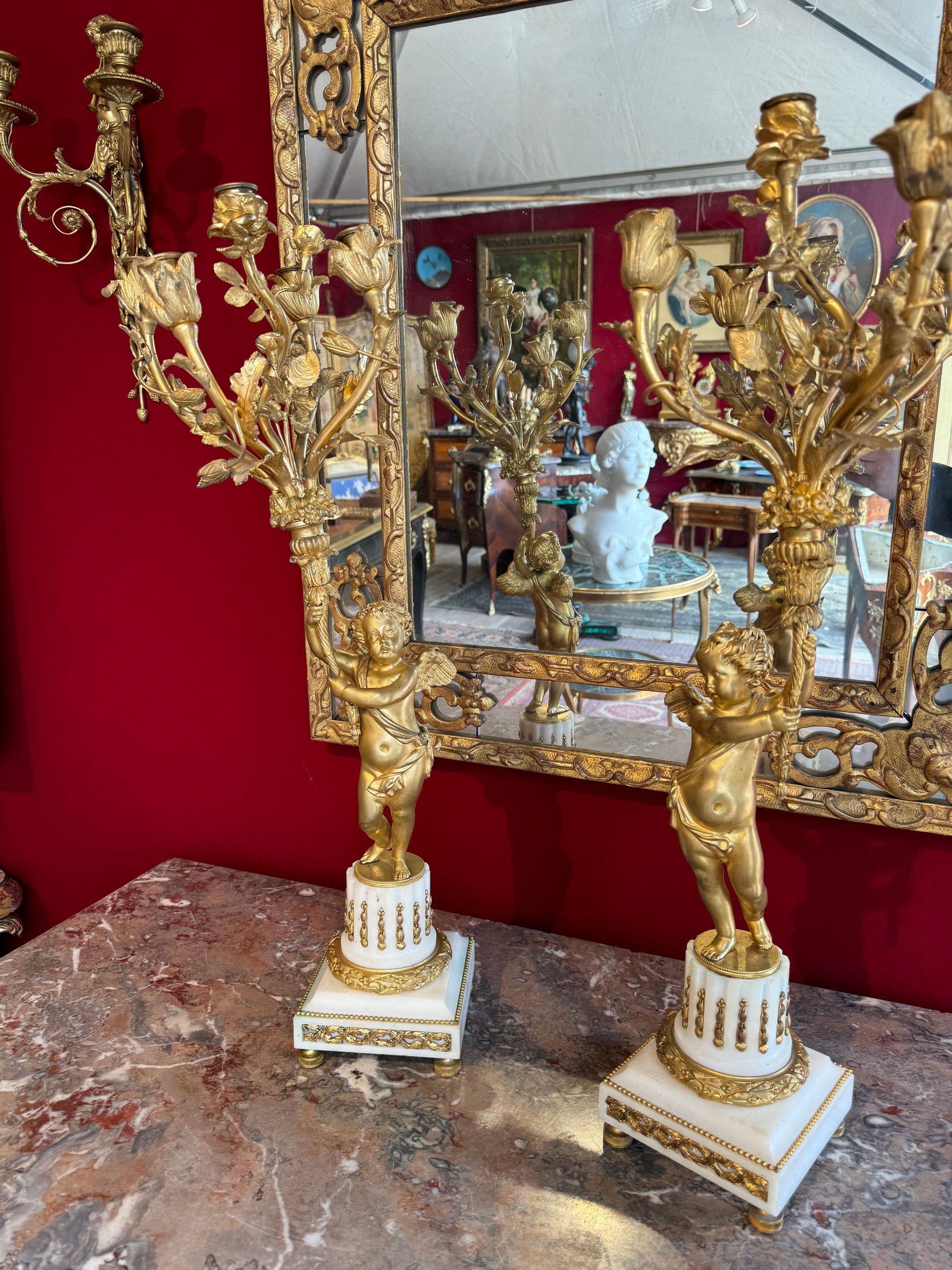 Elégante  paire de candélabres en bronze doré finement ciselé et décoré, de style Louis XVI, époque Napoléon III.
Cette jolie paire de candélabres présente des puttis tenant en main un bouquet floral (de roses) à cinq bras de lumière,
Les puttis sont surelevés par un piedouche et socle en marbre blanc de carrare, finement décoré de frise et se terminant par des petits pieds ronds.
