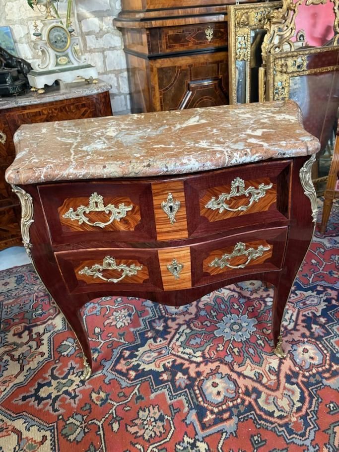 Commode dite sauteuse époque Louis XV – 18ème Portant l’estampille de P.F. GUIGNARD et le poinçonde jurande JME Galbée en façade et sur les côtés, En placage, marquetée de bois de  rose sur fond et d’amarante dans les encadrements, Elle ouvre à deux tiroirs avec poignées de tirage de chaque côté et entrée dans son milieu,  Elle propose une chute de bronze finement ciselé sur les côtés et les sabots et repose sur des pieds cambrés. Le tout coiffé d’un épais marbre brèche d’Alep, A propos de : Pierre-François Guignard Pierre-François Guignard (1740-1794) Ébéniste. Paris. Maître le 21 janvier 1767. Il s'établit fabricantet marchand de meubles rue de la Roquette. Guignard a laissé de bons meubles tant Louis XV que Transition ou Louis XVI.