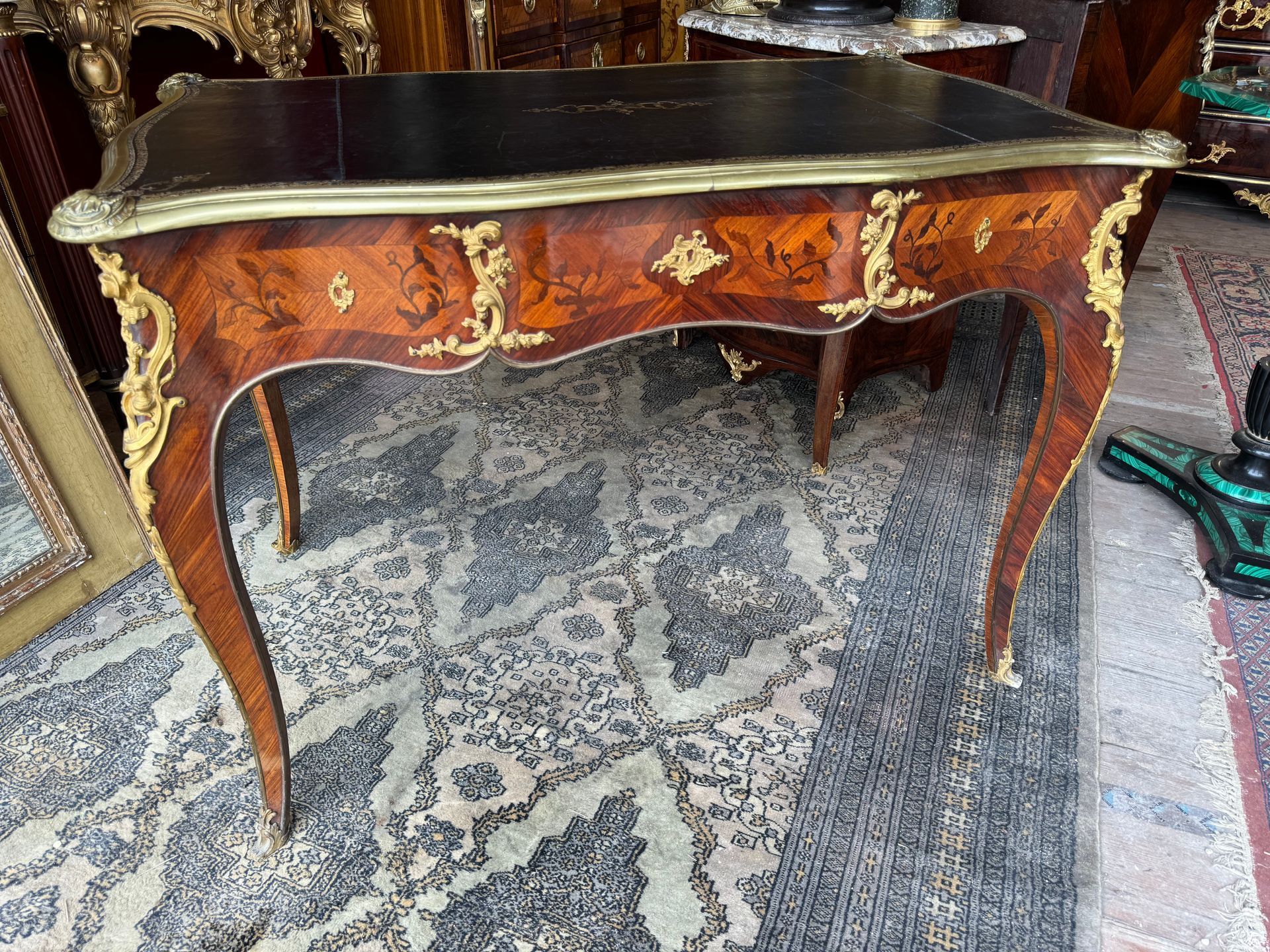 Bureau plat de style Louis XV, toutes faces,  fortement mouvementé,
Il est en bois de rose et palissandre, et présente une marqueterie de fleurs et feuillages,
Il repose sur quatre pieds cambrés se terminant par des sabots et ouvre par trois tiroirs en ceinture en façade et trois faux tiroirs à l’arrière,
Il est enrichi d’une ornementation de bronzes dorés de très fine qualité,
Le plateau du bureau est recouvert d'un cuir de couleur noir entouré d'une frise et motifs doré,  entouré d'une lingotière.
Bureau de belle facture - travail parisien du XIXème dans le goût de Gervais Durand.