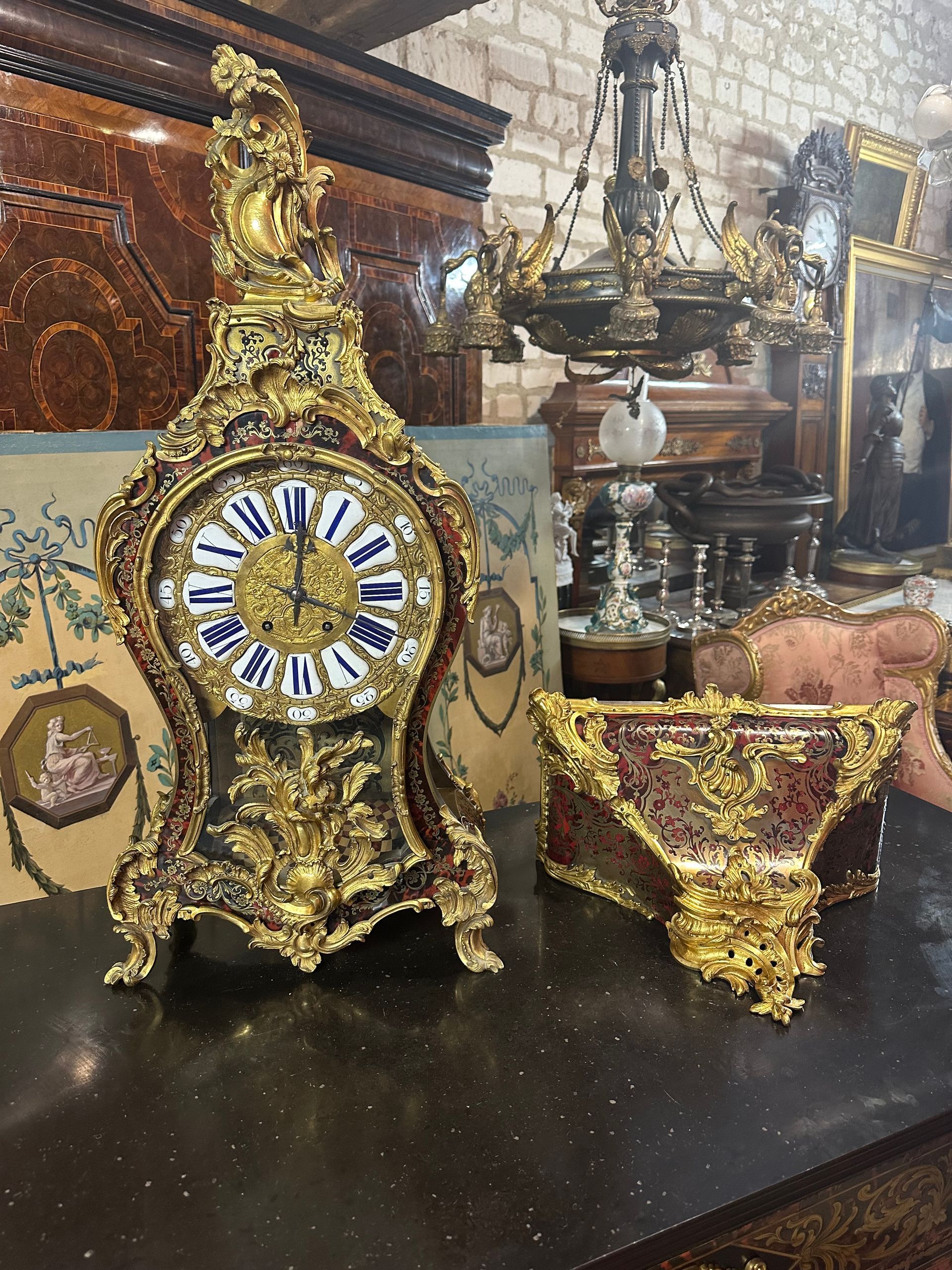 Grand cartel et son cul-de-lampe de forme violonée, en marqueterie Boulle et laiton d’époque Napoléon III – 19ème, de style Louis XV
L’ensemble offre un riche décor de feuillage et de petites fleurs agrémenté de bronze doré et ciselé;
Le cadran est à douze cartouches émaillés de couleur bleue:  chiffres romains pour les heures et douze petits chiffres arabes pour les minutes.
Balancier soleil.
Ce cartel est dans son état d’origine,
Hauteur du cartel seul  : 80 largeur de base 36
Hauteur de la console seule : 37 largeur 44
