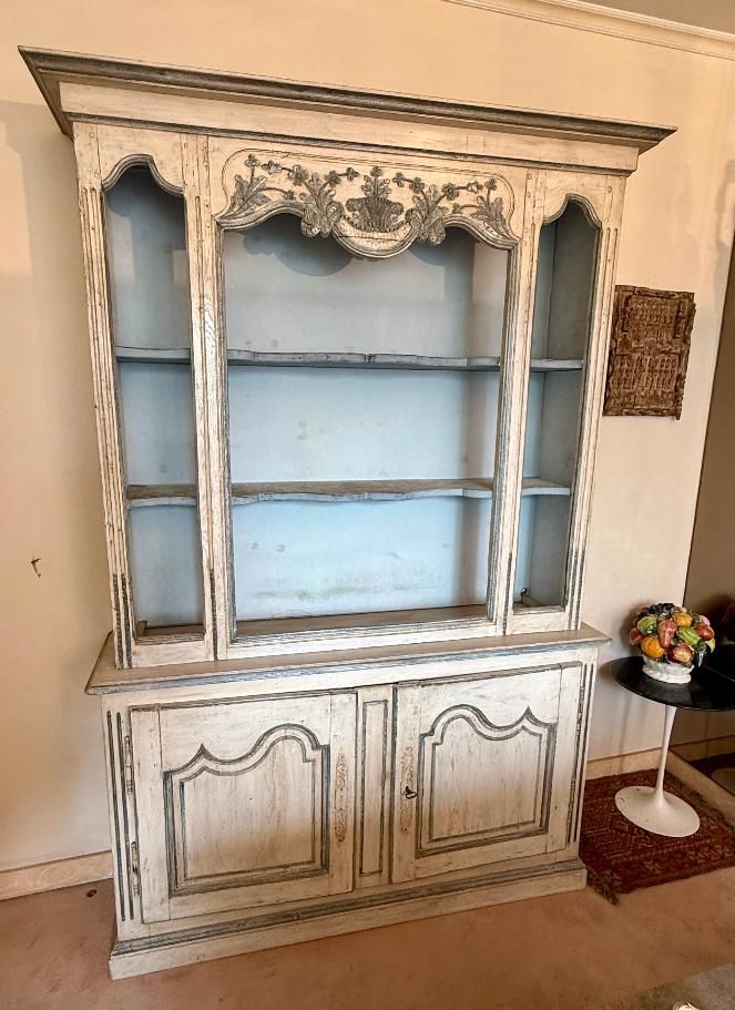 Buffet deux corps de style Louis XIV  provençal,  composé d’éléments datant du 18e siècle, en bois peint patiné à l’antique,  Buffet sur plinthe, Il présente : - deux étagères de forme mouvementées en partie haute (pour présentation) - et deux portes moulurées offrant une étagère intérieure en partie basse, Belle sculpture florale avec panier fleuri en partie haute dans son milieu.