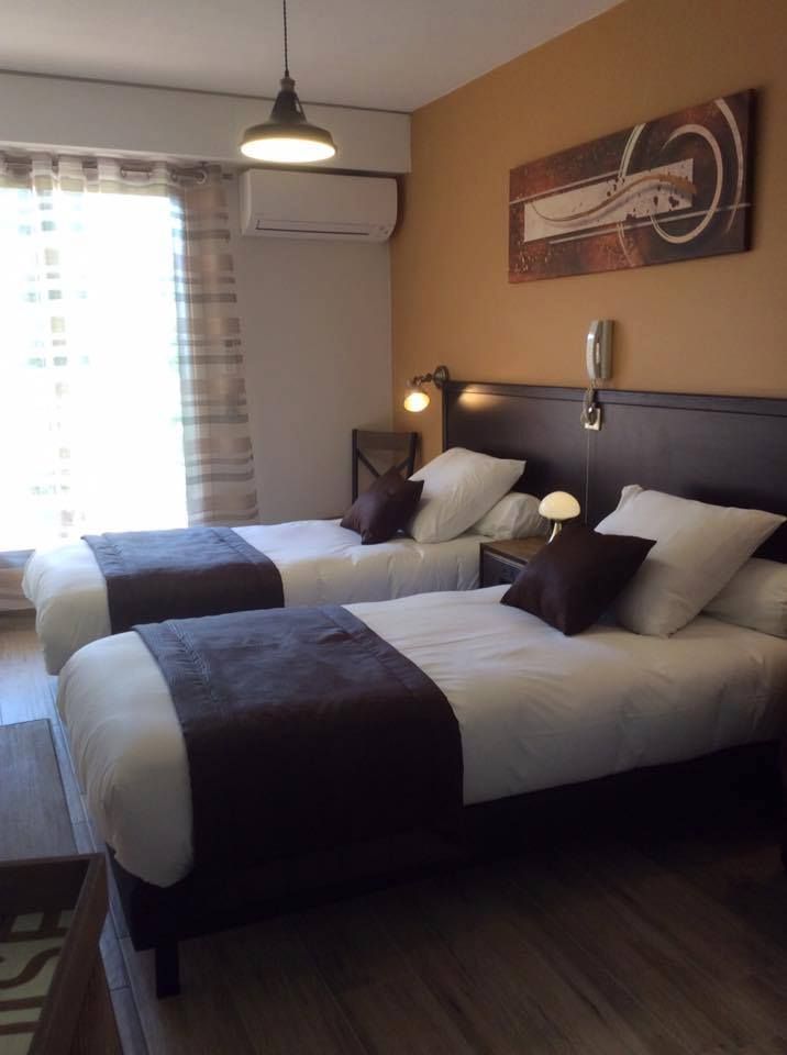 Lits jumeaux dans une chambre d'hôtel avec du linge de lit marron et blanc.