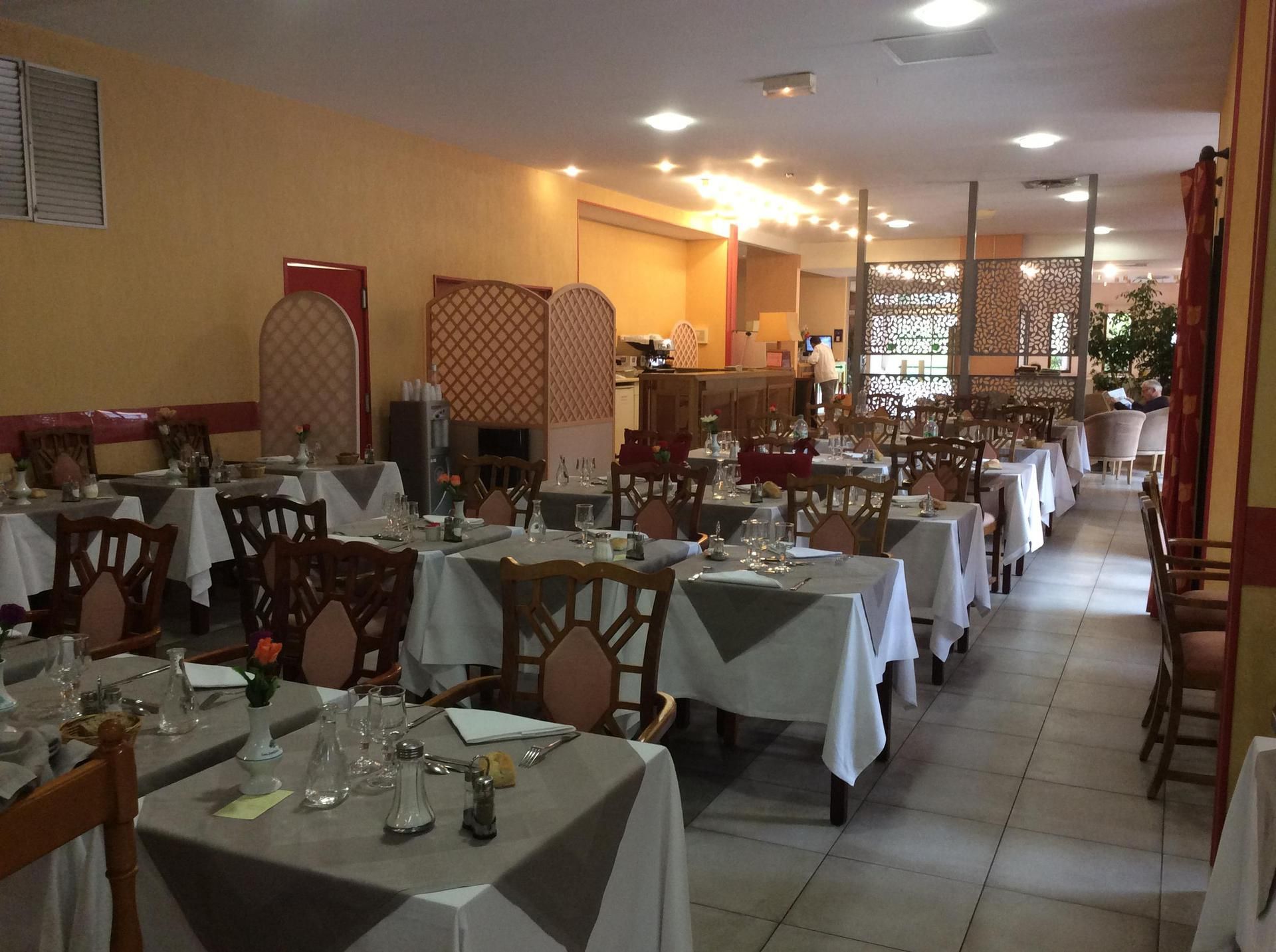Intérieur d'un restaurant avec tables dressées, tons neutres et paravents décoratifs.