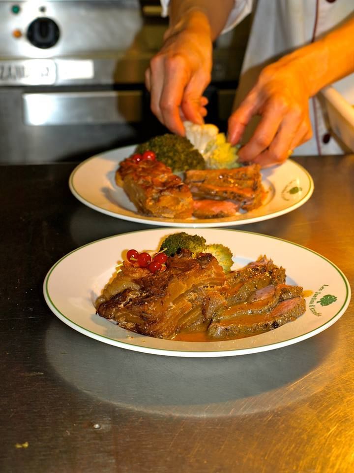 Deux assiettes dressées ; le chef ajoute la garniture. Viande brune, légumes verts, assiettes blanches.