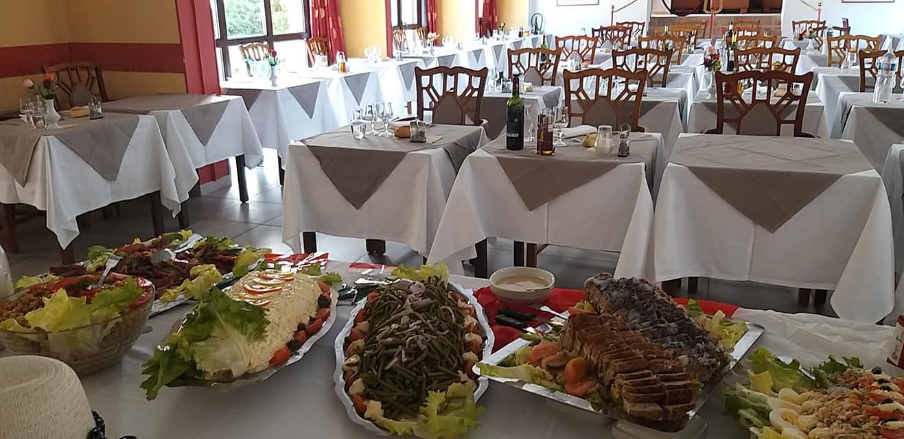 Une salle à manger avec des tables dressées pour un repas et un buffet au premier plan.