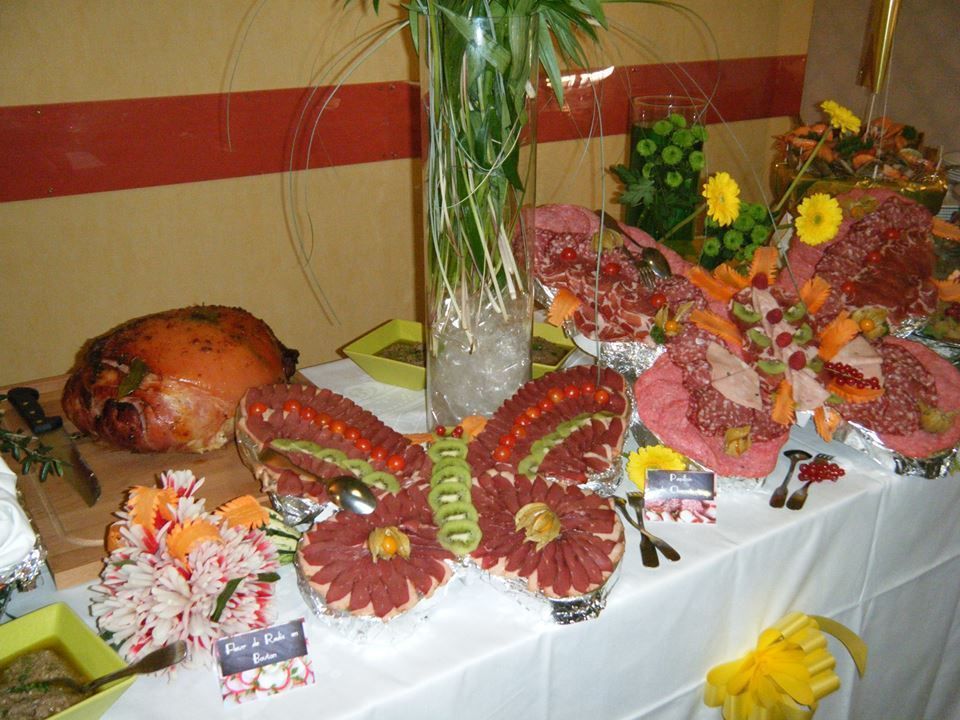 Buffet avec des mets en forme de papillon et de fleurs, ainsi que diverses viandes et fruits exposés.
