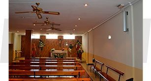 Una iglesia con bancos de madera y un ventilador de techo.