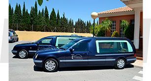 Dos coches fúnebres están estacionados frente a un edificio.