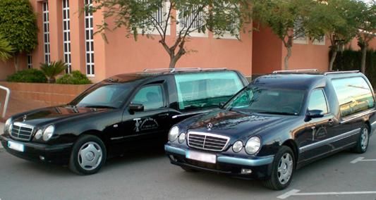 Dos coches negros están aparcados uno al lado del otro delante de un edificio.