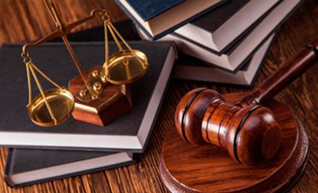 Un mazo de juez, una balanza de justicia y libros sobre una mesa de madera.