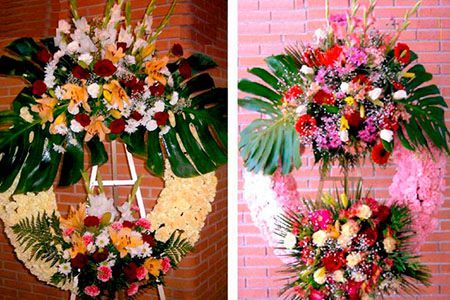 Dos coronas de flores cuelgan de una pared de ladrillos.