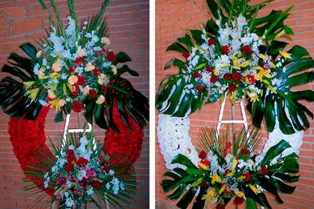 Dos coronas de flores cuelgan de una pared de ladrillos.
