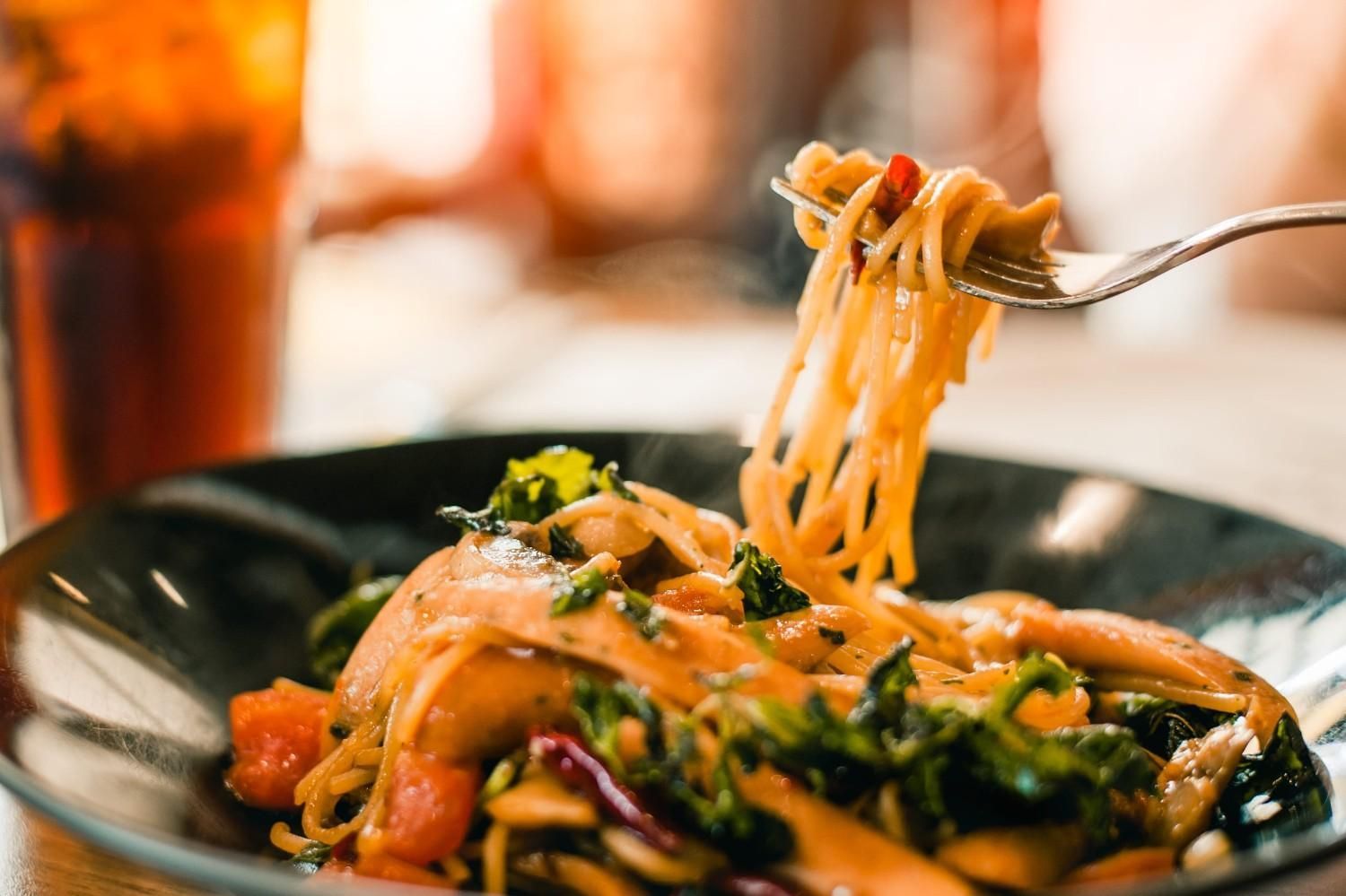 Una carretilla elevadora coloca los espaguetis sobre un plato de pasta con verduras salteadas.